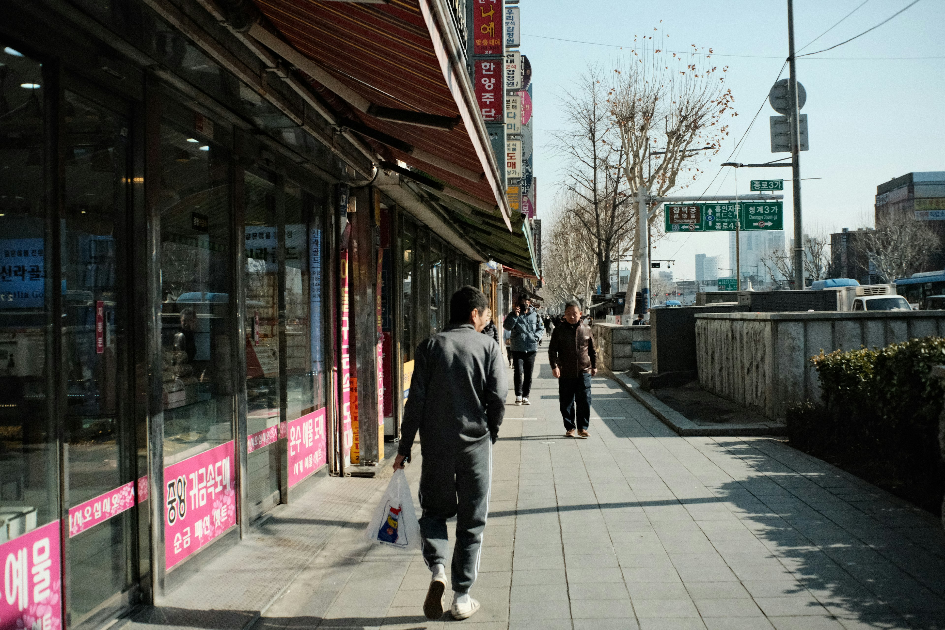 상점과 나무가 있는 보도를 걷는 사람들