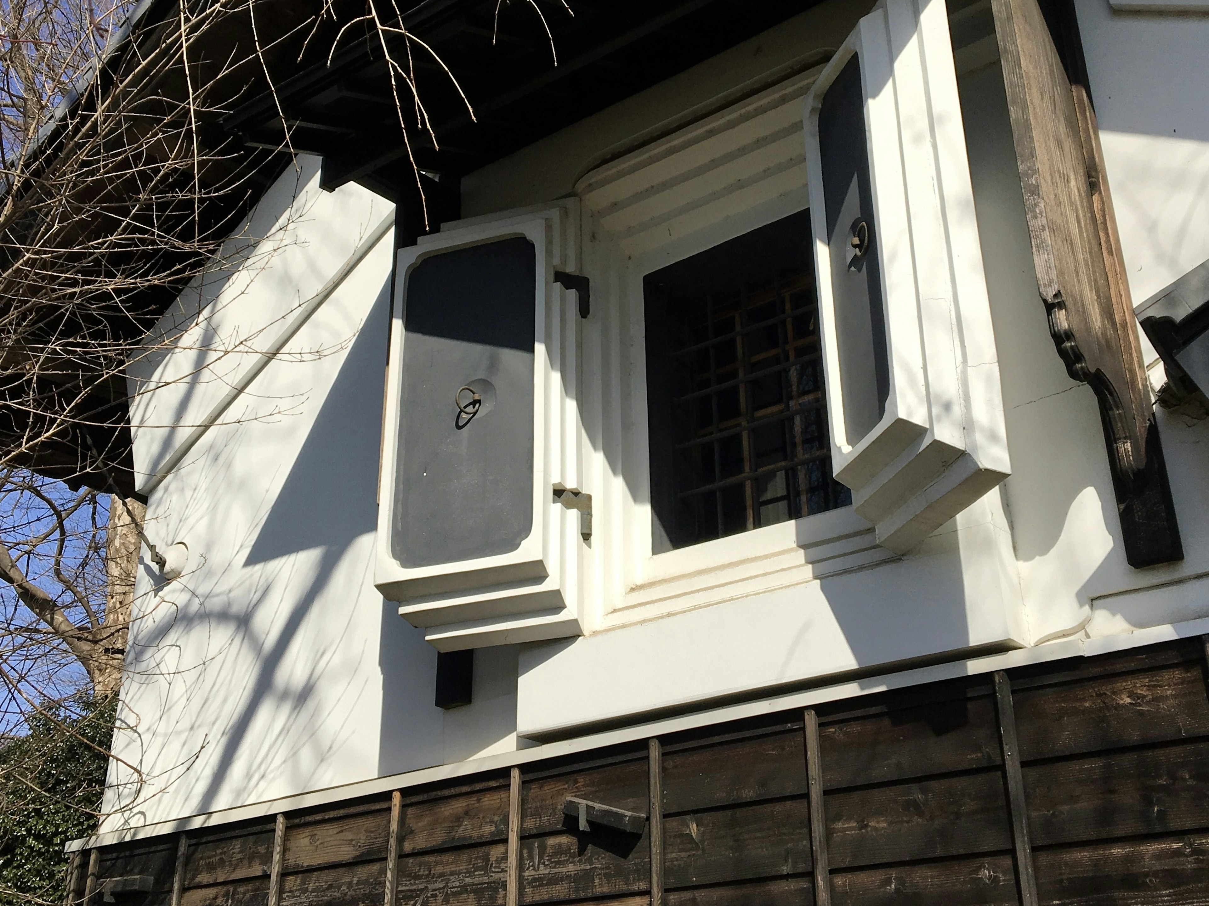 Ein altes Haus mit einem weißen Fenster und offenen Fensterläden