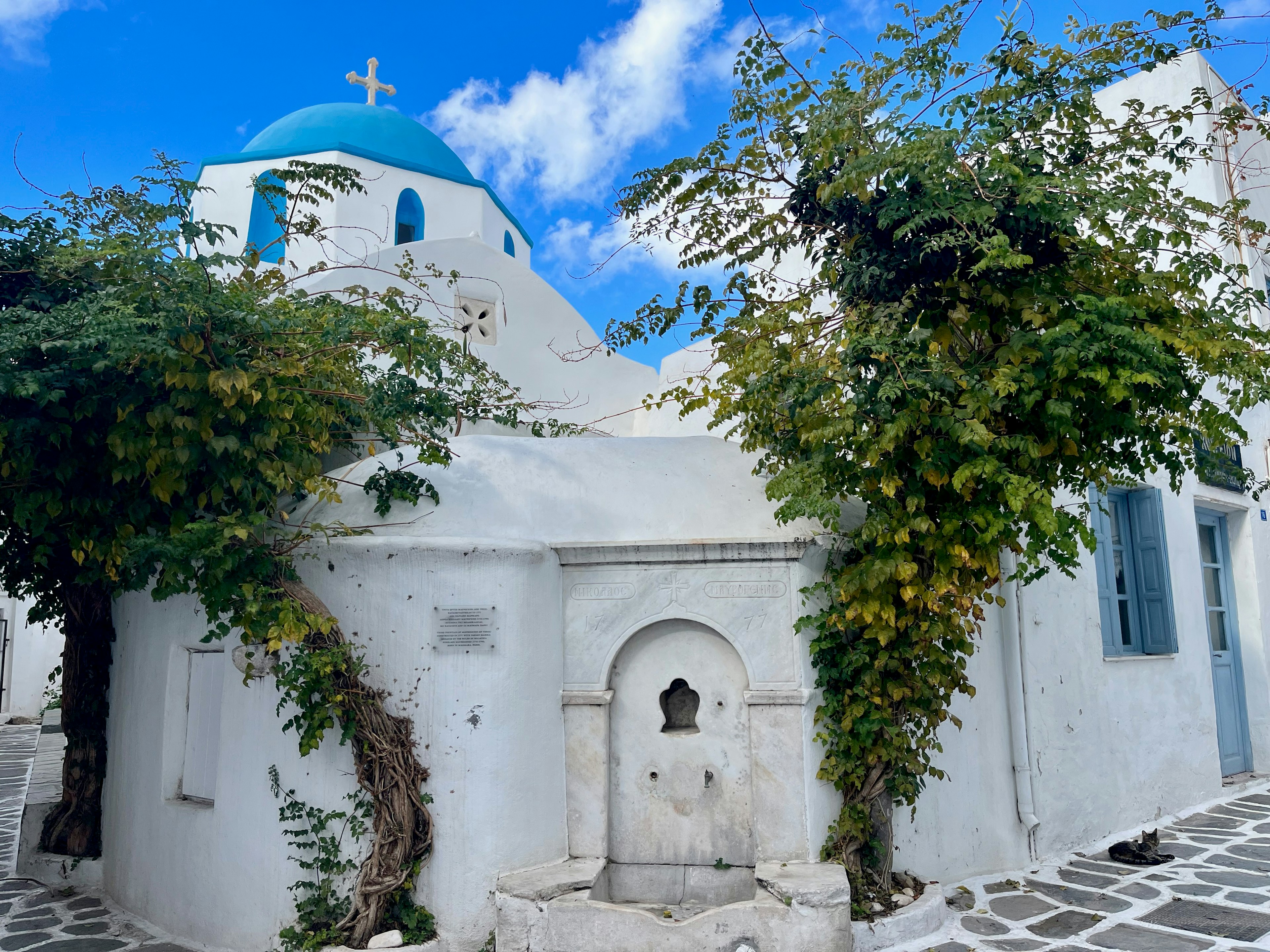 Charming white building with a blue dome and lush greenery