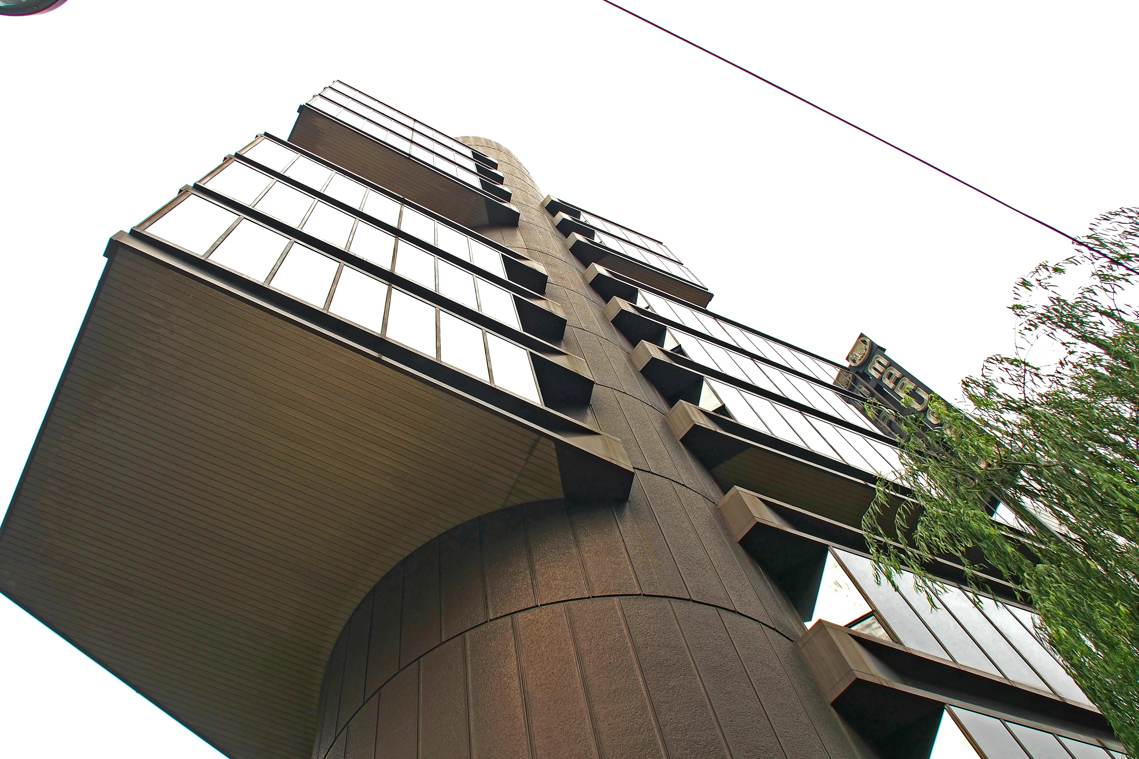 Modern architectural structure viewed from a low angle featuring a contrast of metal and glass against a bright sky