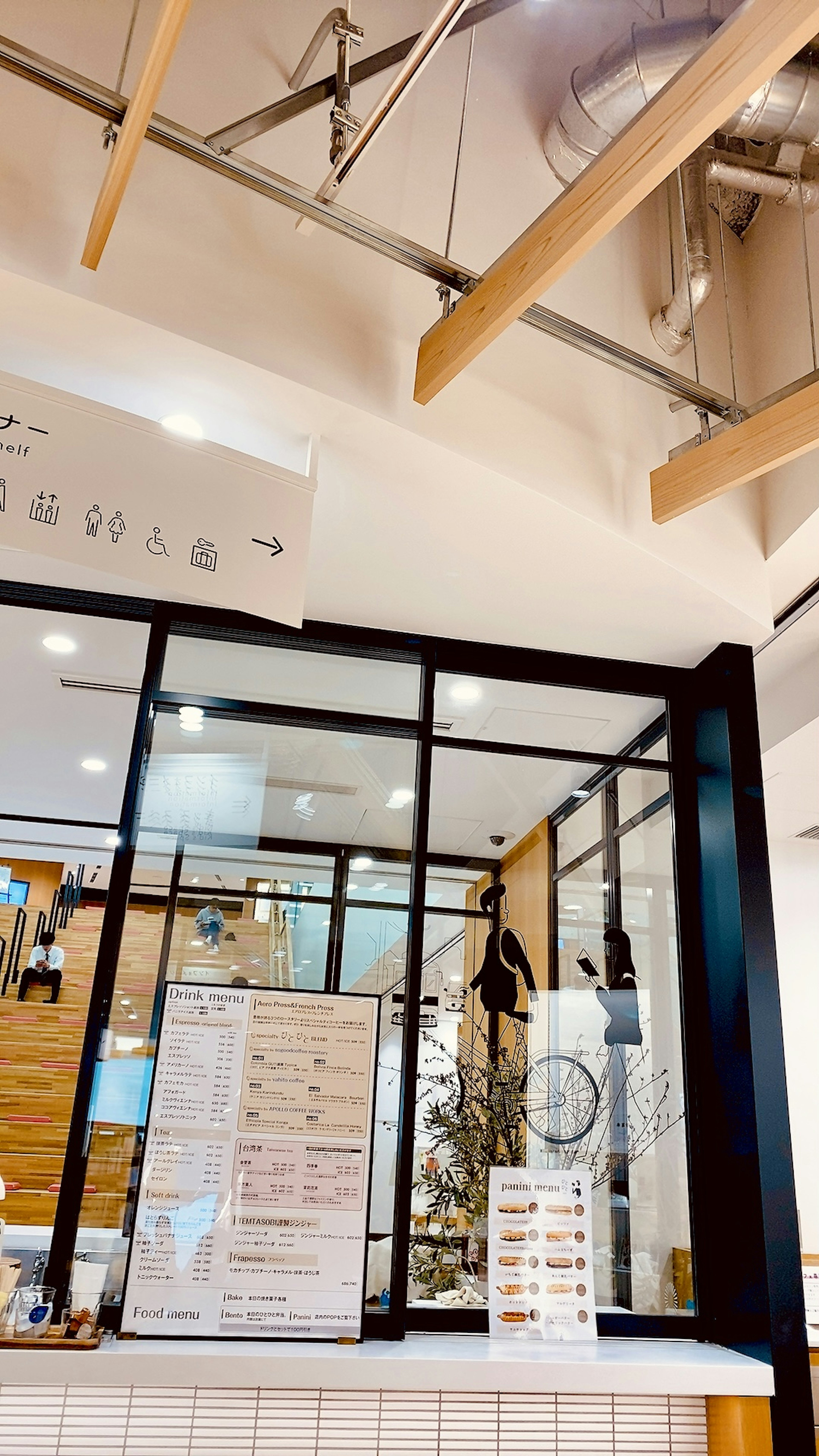 Modern cafe interior featuring glass windows wooden beams and a menu display at the counter