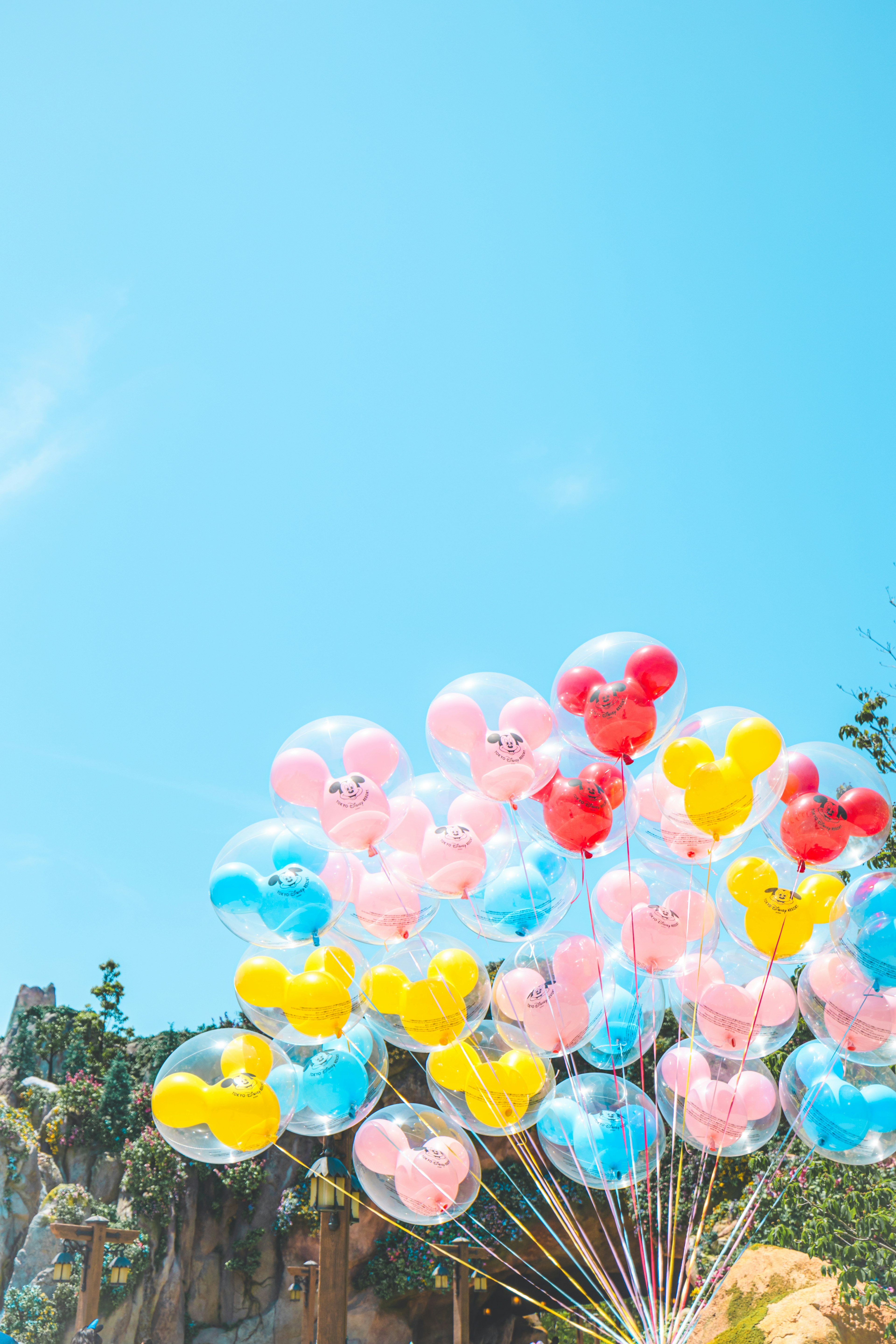 A colorful bundle of Mickey balloons under a blue sky