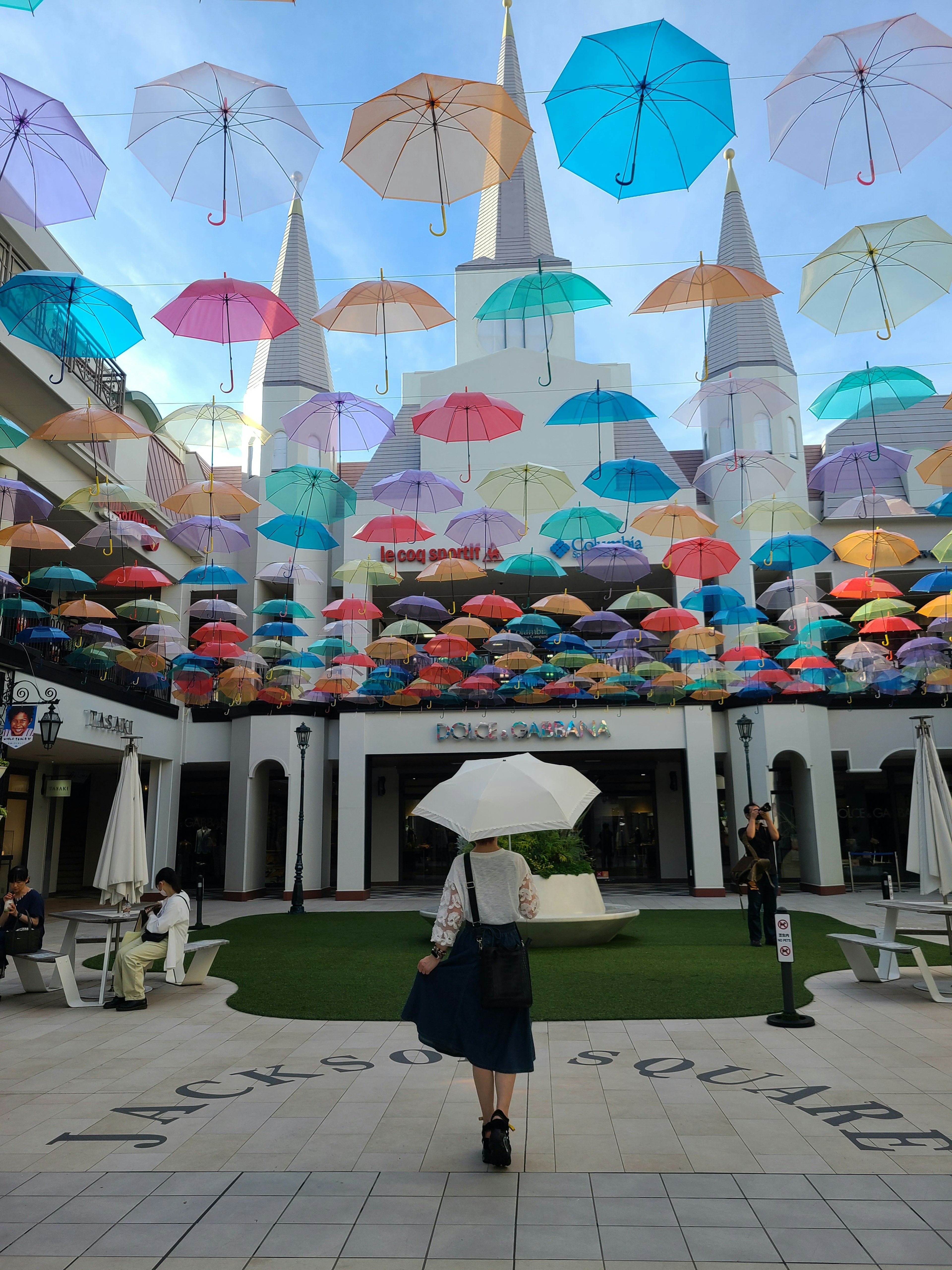 Femme marchant sous des parapluies colorés dans une cour vibrante