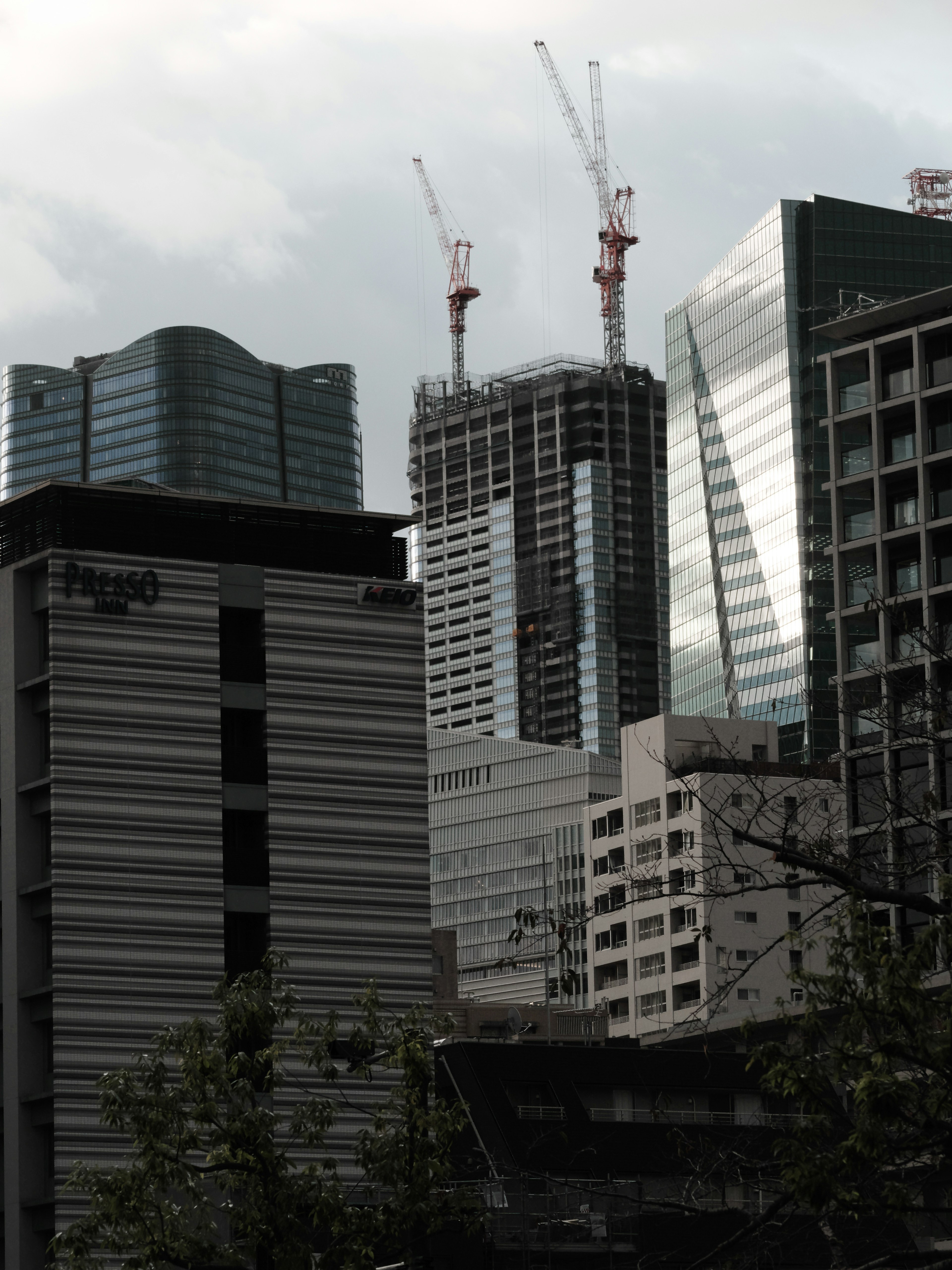 Garis langit perkotaan dengan gedung pencakar langit dan crane konstruksi