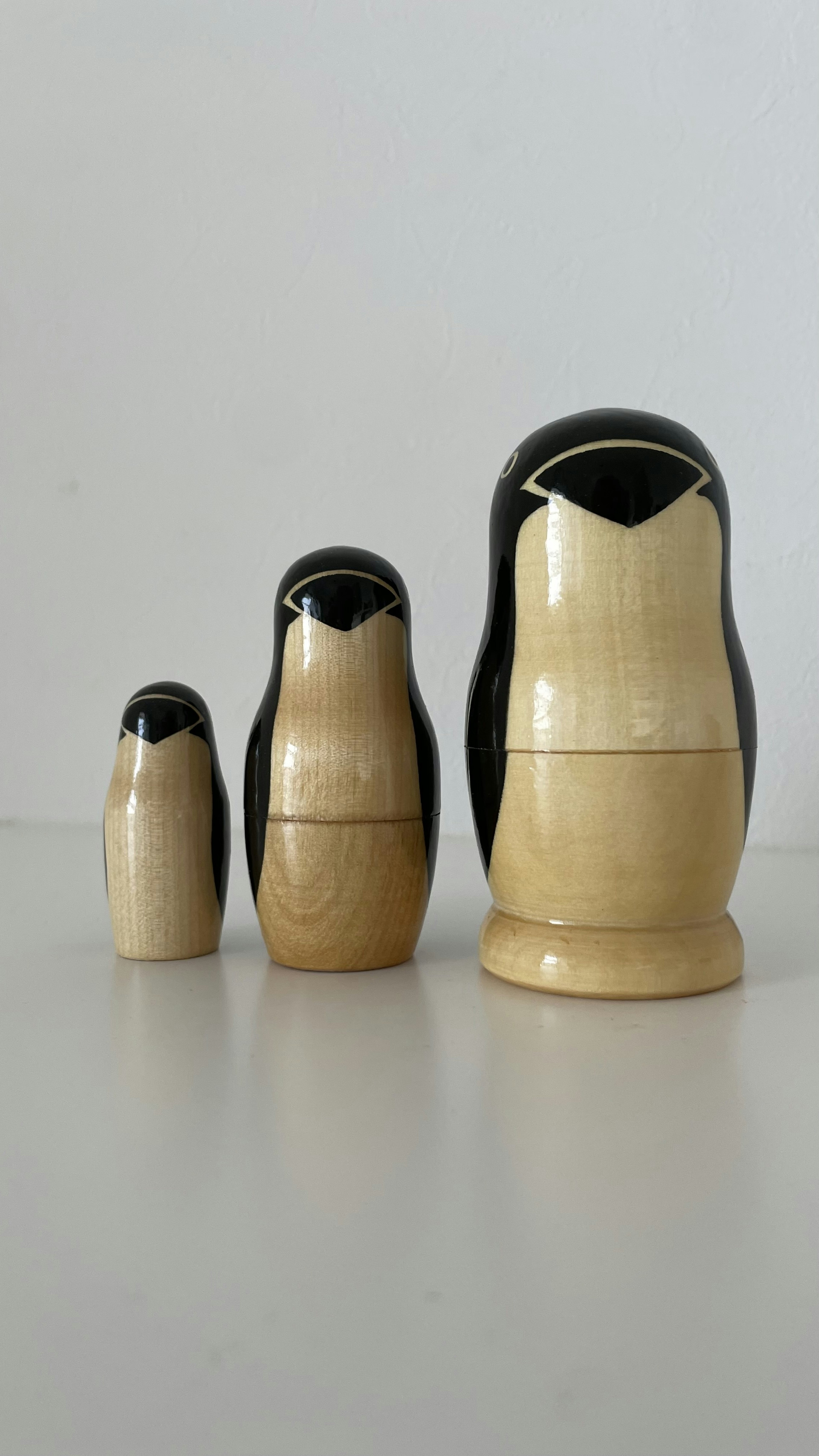 Three nesting penguin dolls of different sizes arranged in a row