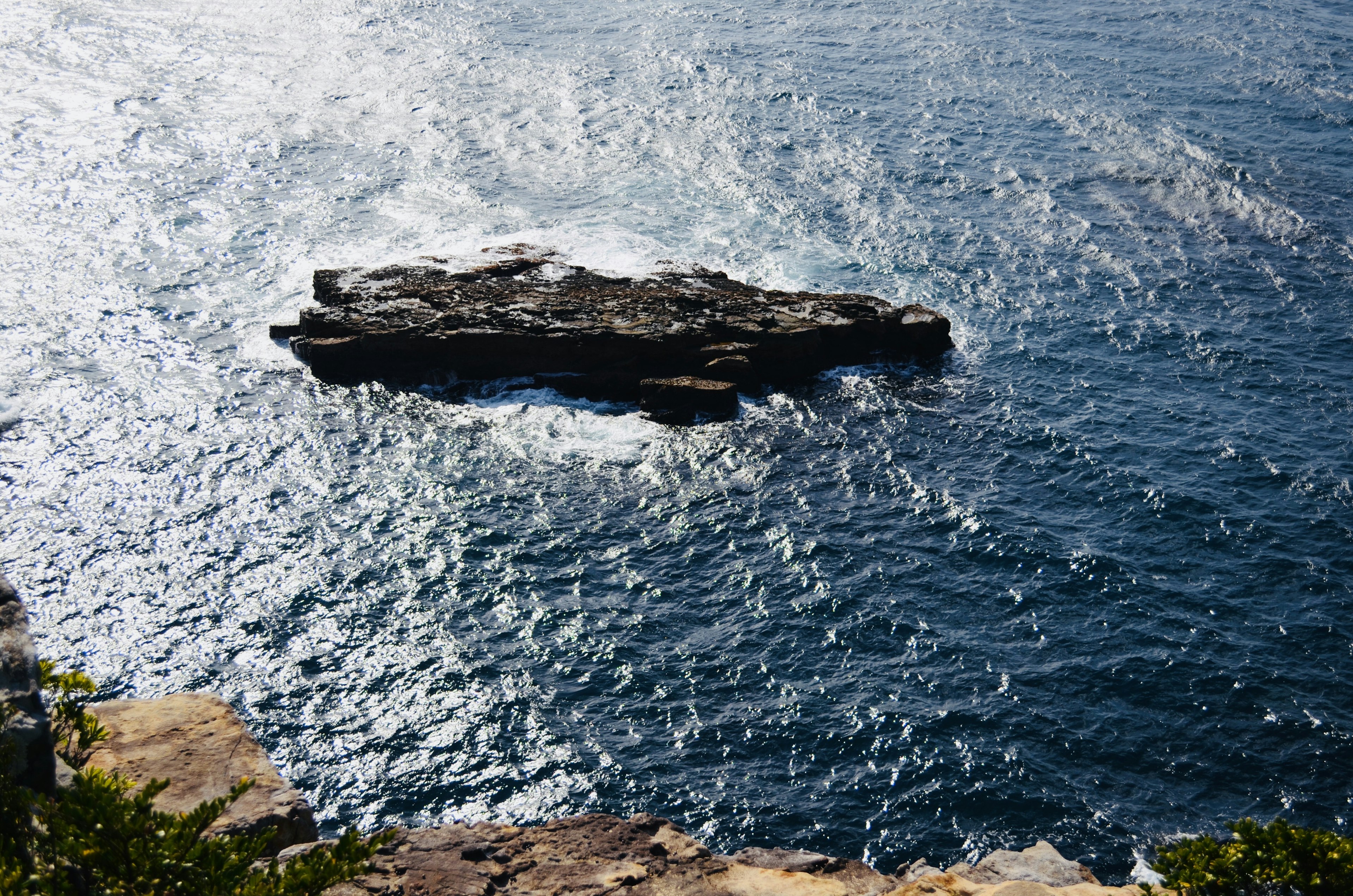 Un rocher flottant sur l'eau avec des vagues scintillantes