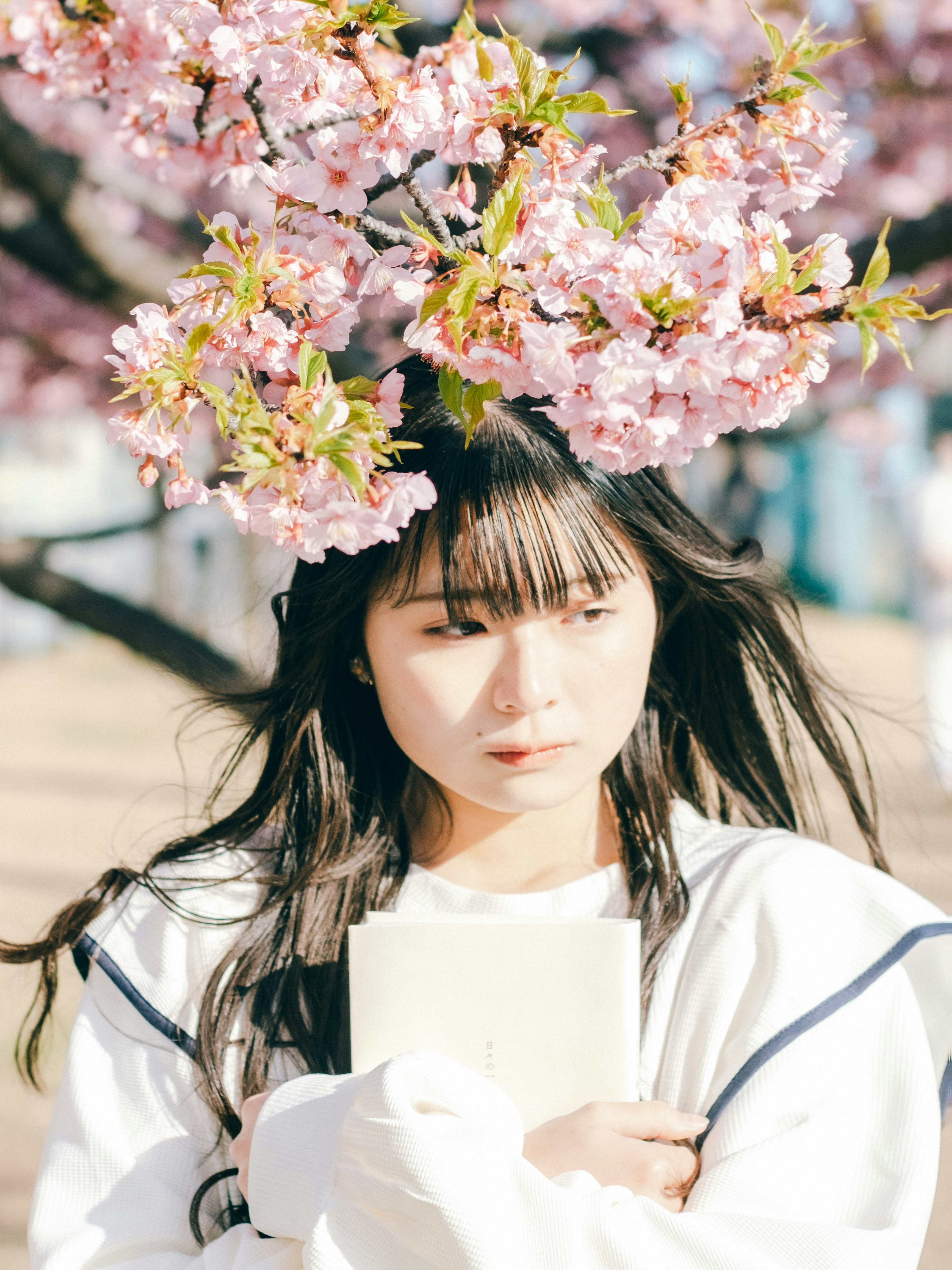 Woman wearing white clothing standing under cherry blossoms