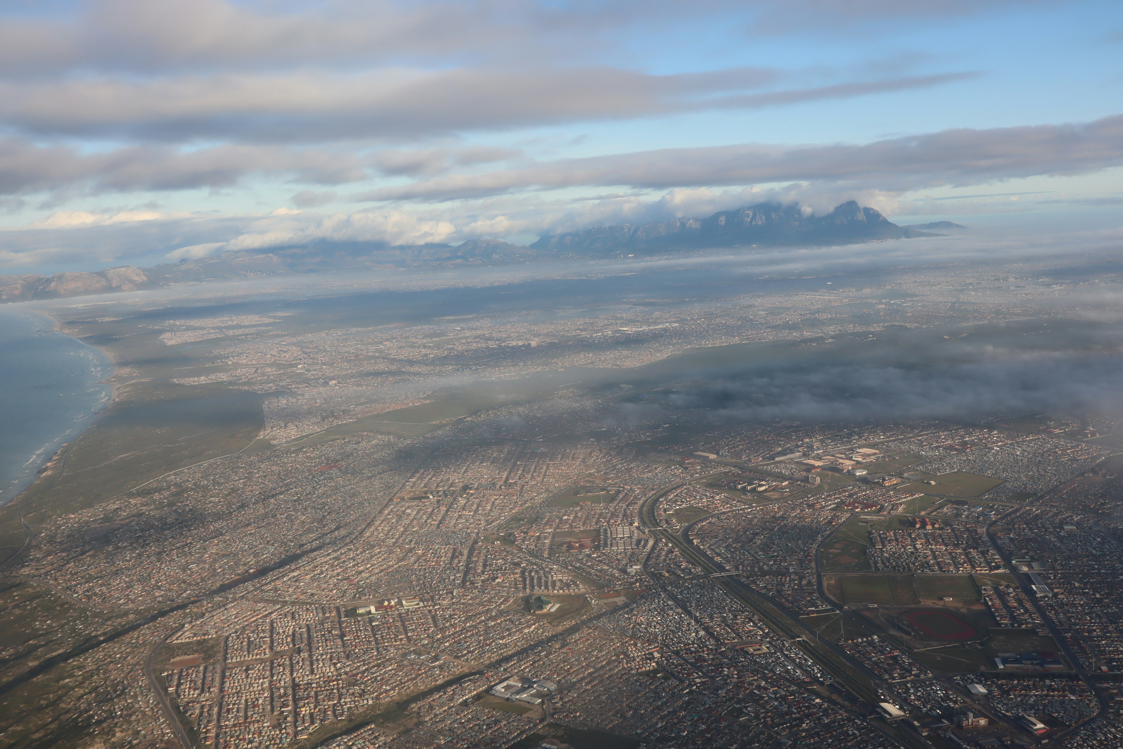 Aerial view of a city with ocean and mountains in the background