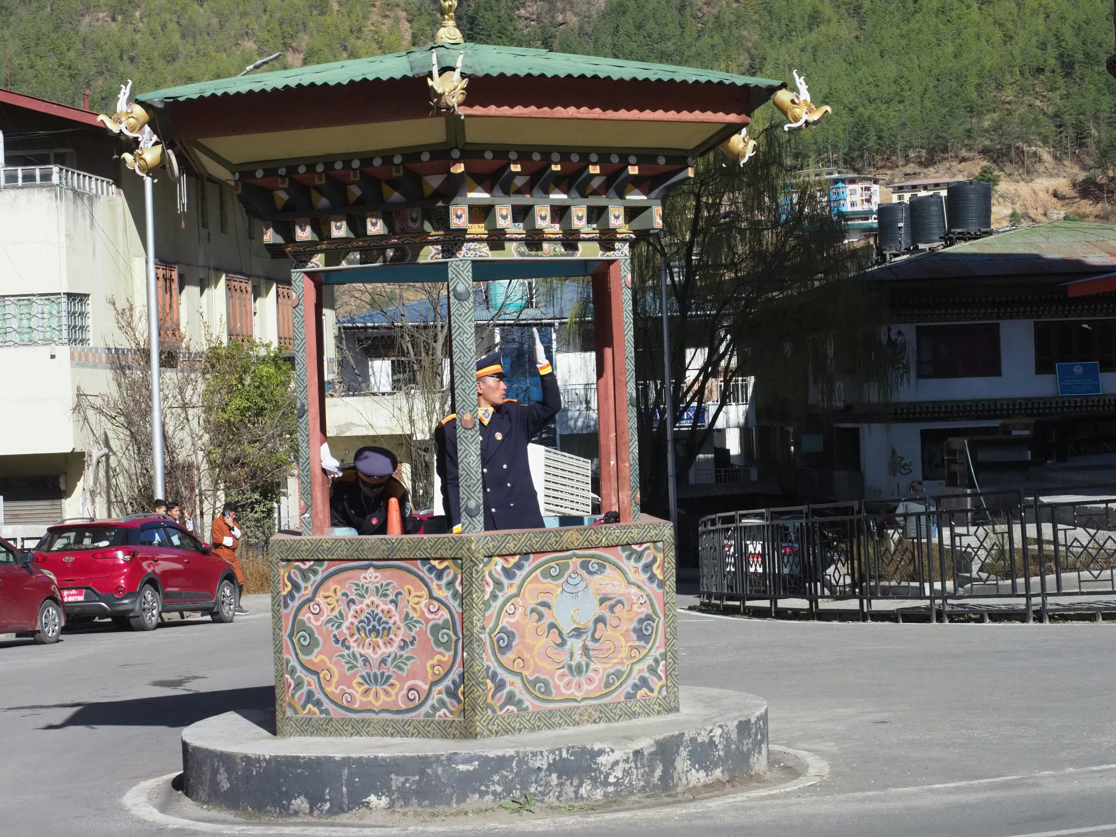 Traditional decorative well structure at the center surrounded by modern buildings and cars