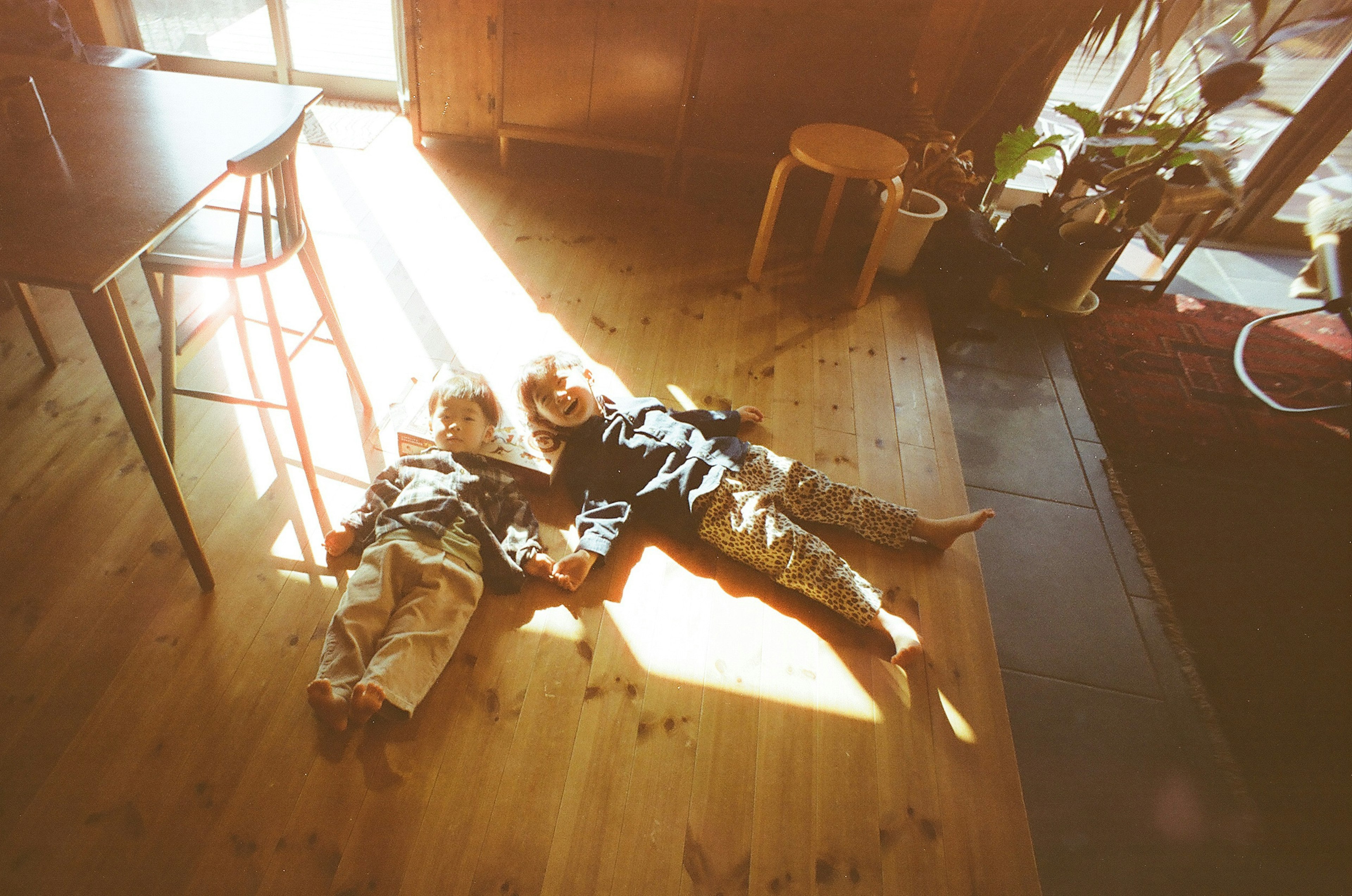 Enfants allongés sur le sol au soleil avec un parquet en bois