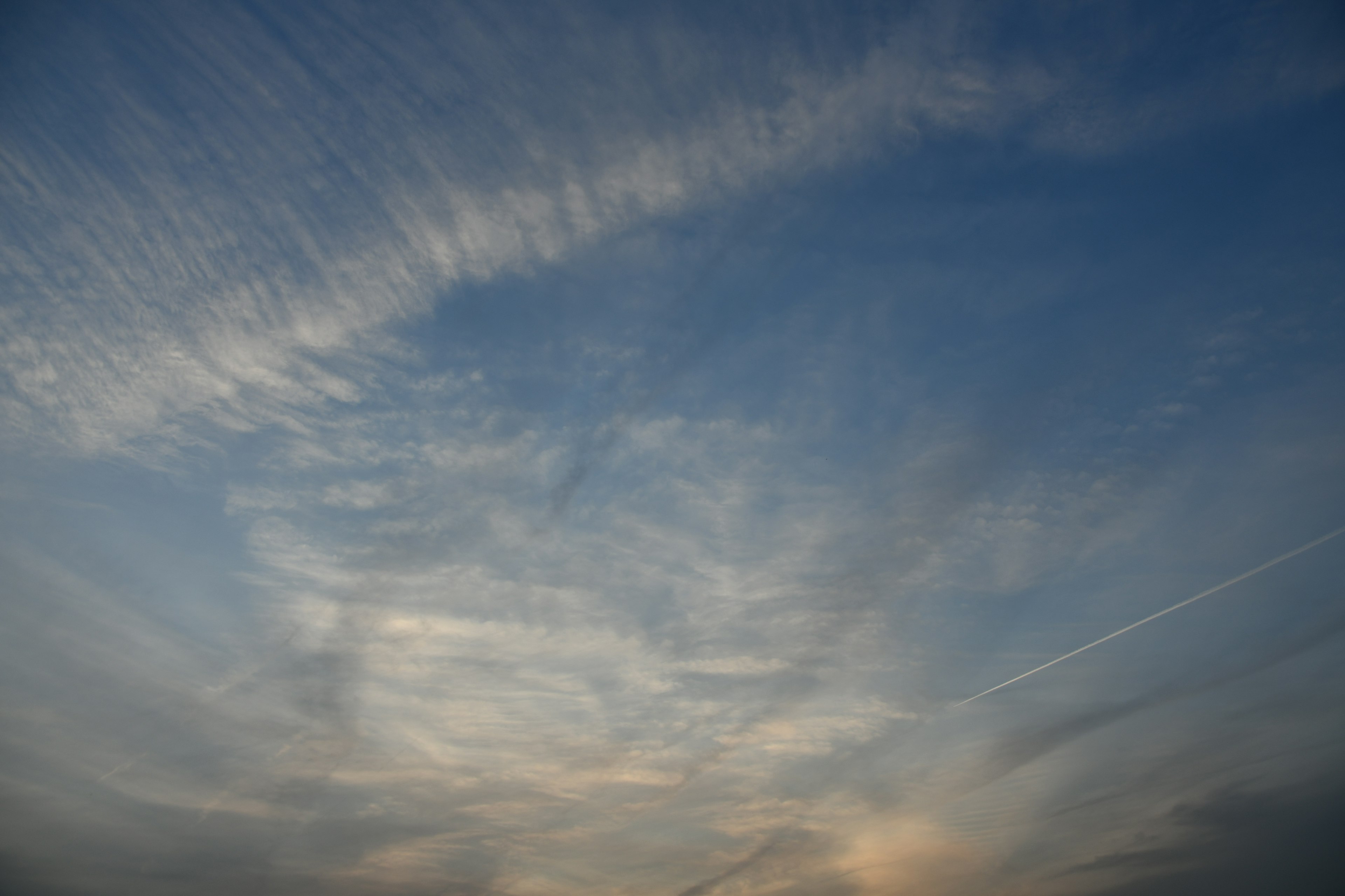 A pattern of clouds spreading across a blue sky with soft hues