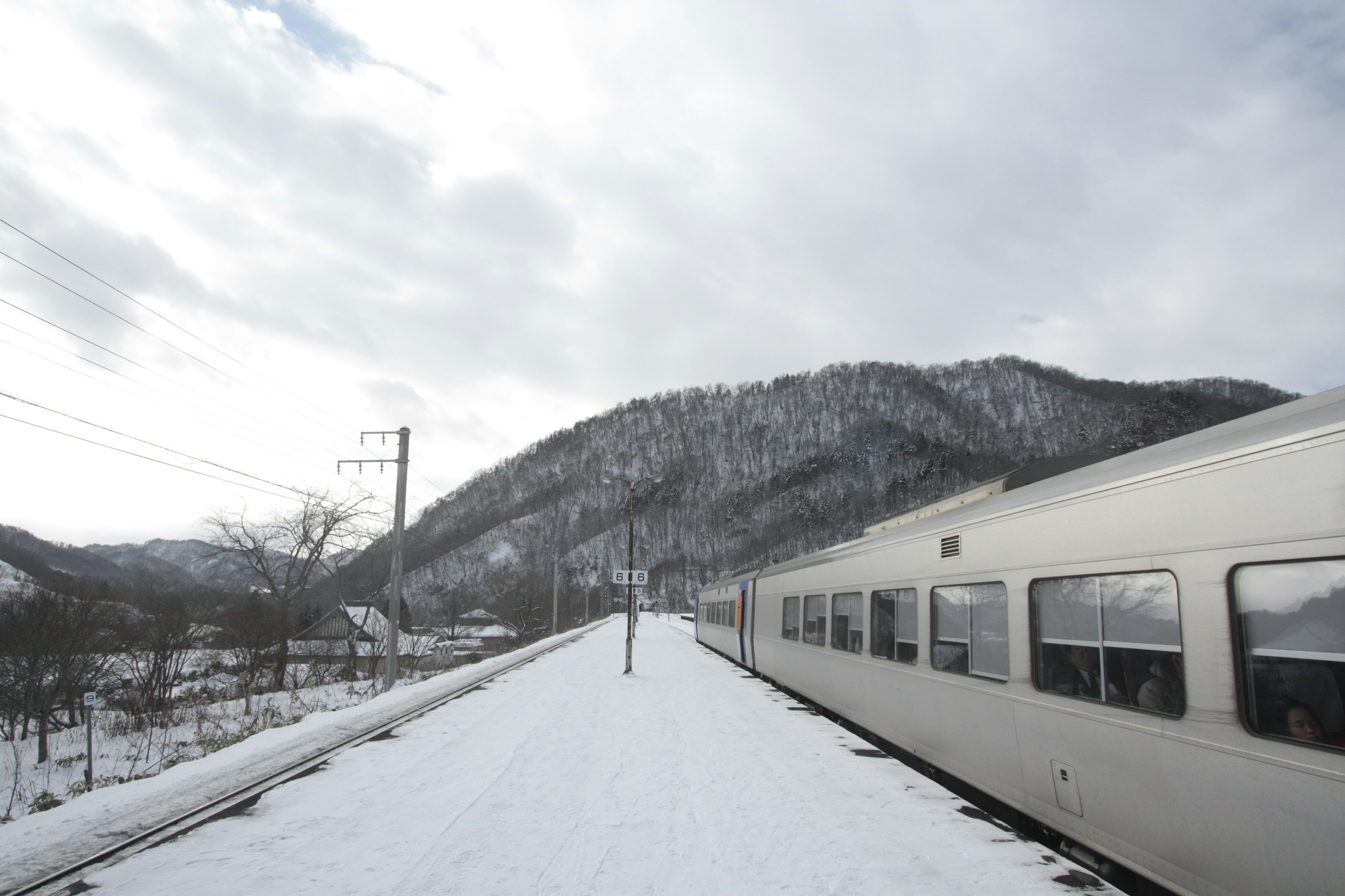 Platform kereta yang tertutup salju dengan latar belakang gunung