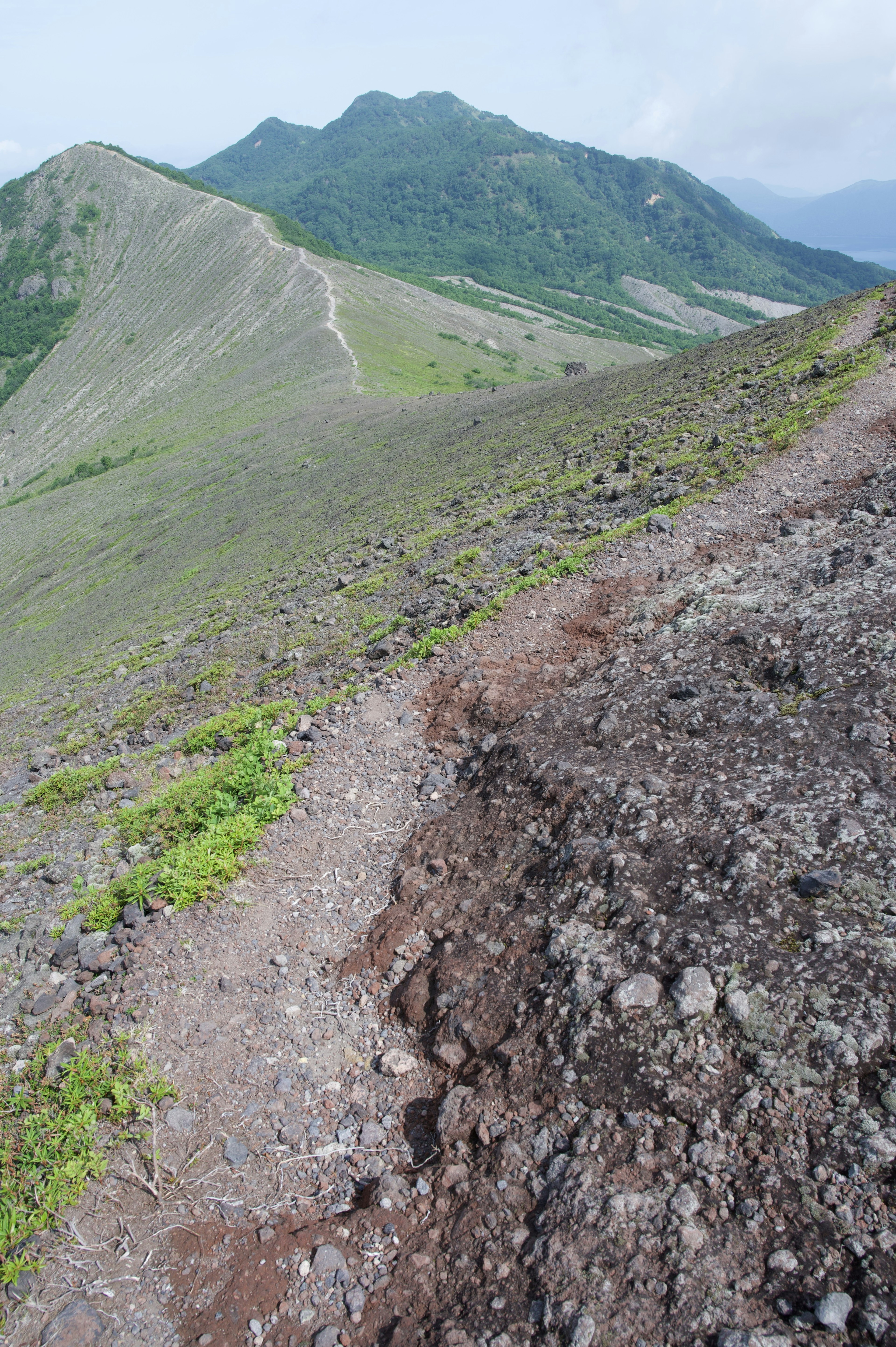 緑の丘陵と険しい小道が続く風景