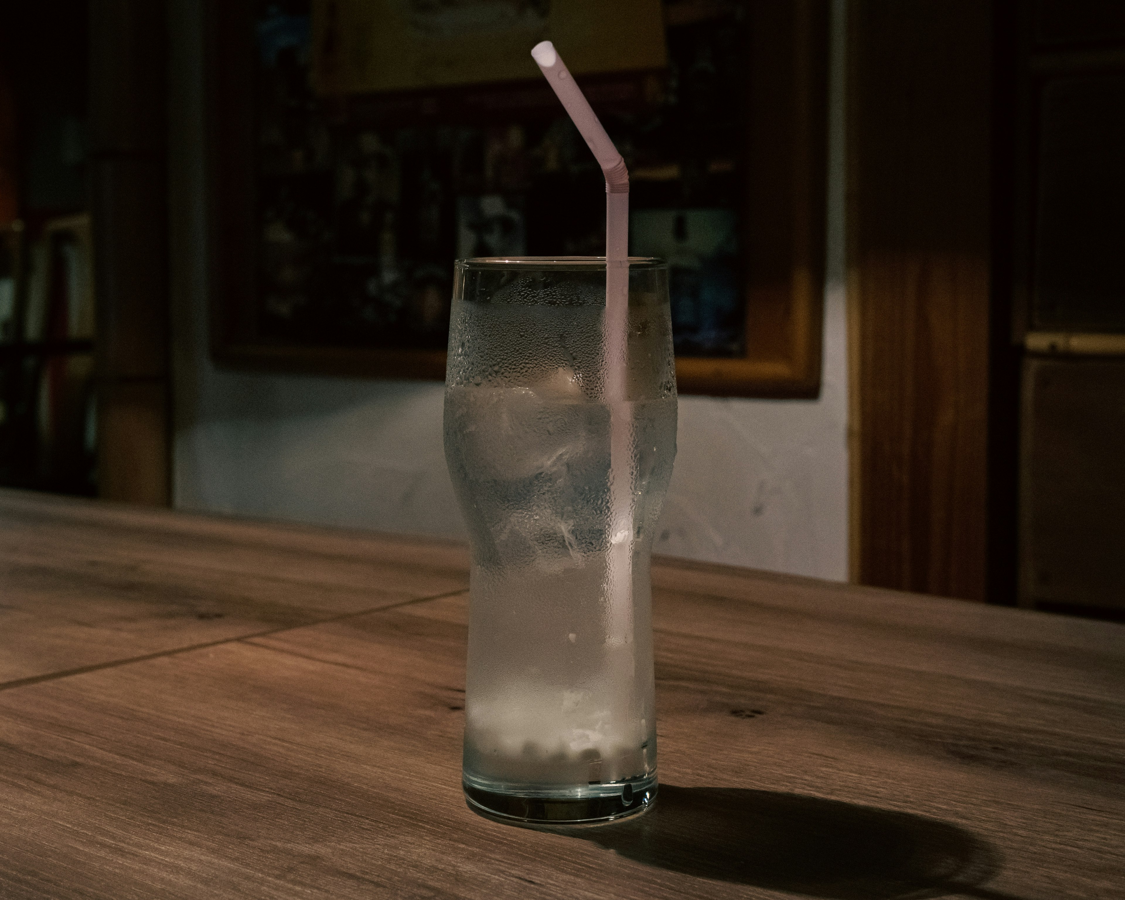 Un vaso transparente con hielo y una pajilla