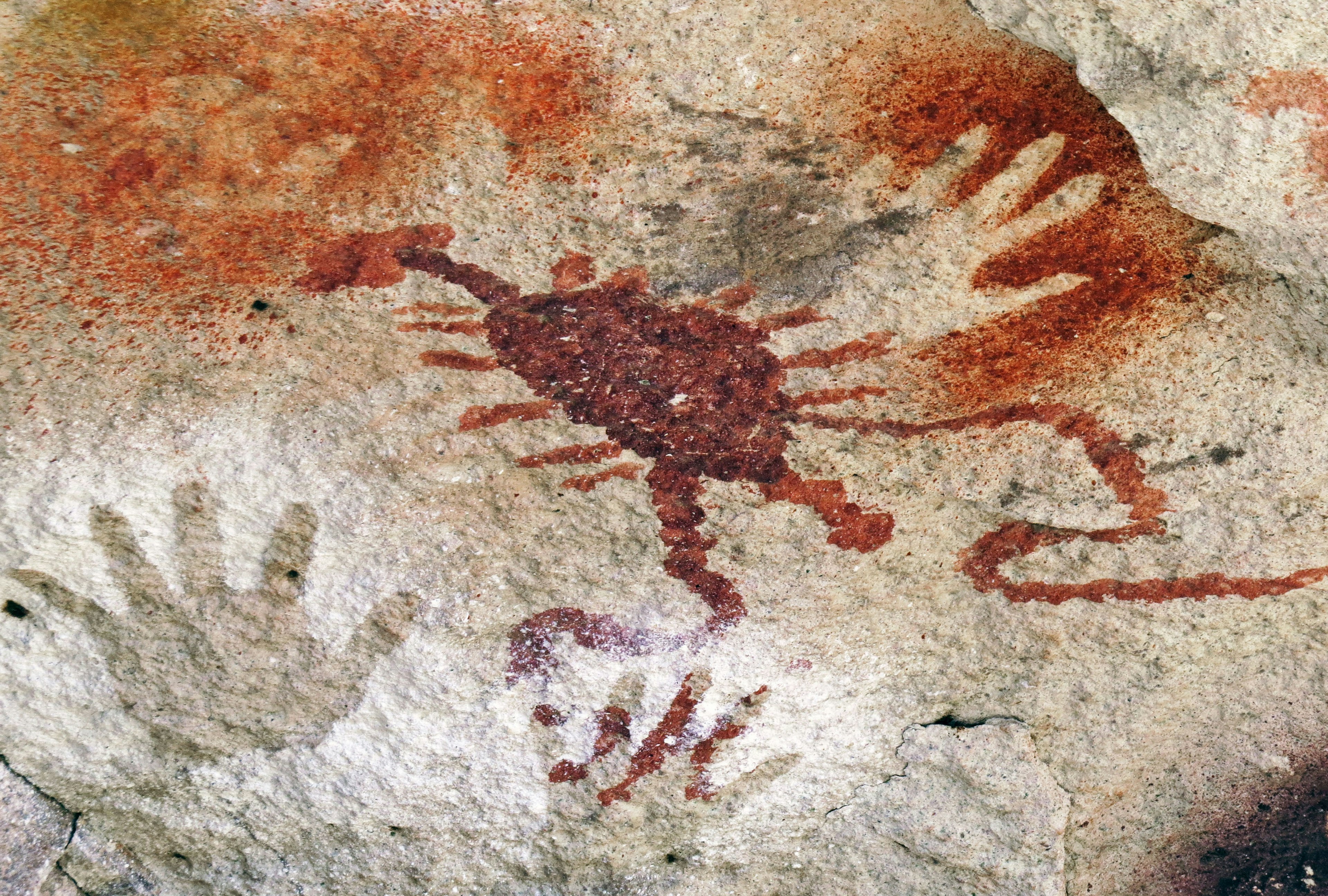 Ancient cave painting featuring handprints and a scorpion