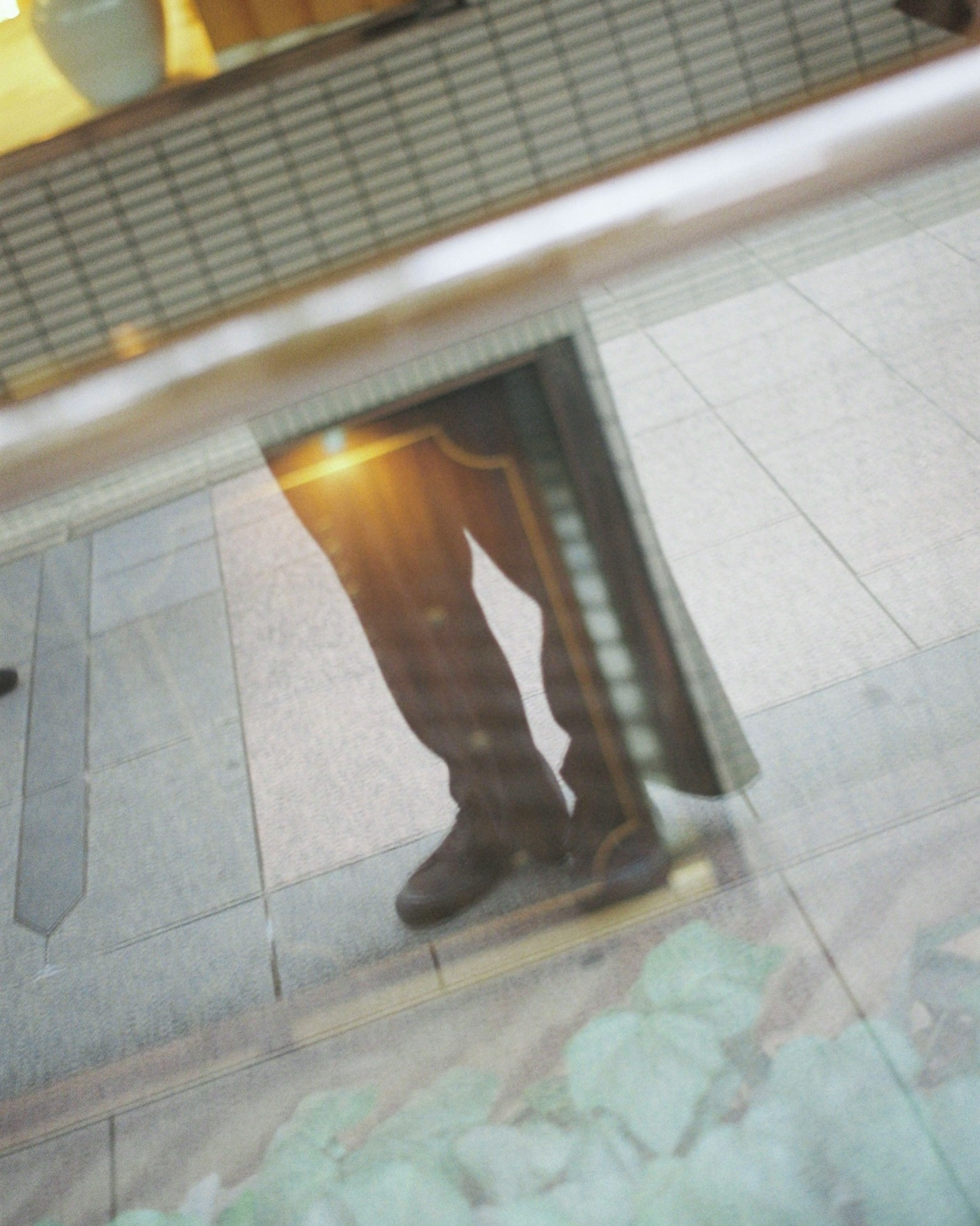 Reflection of a person's legs and surroundings in glass