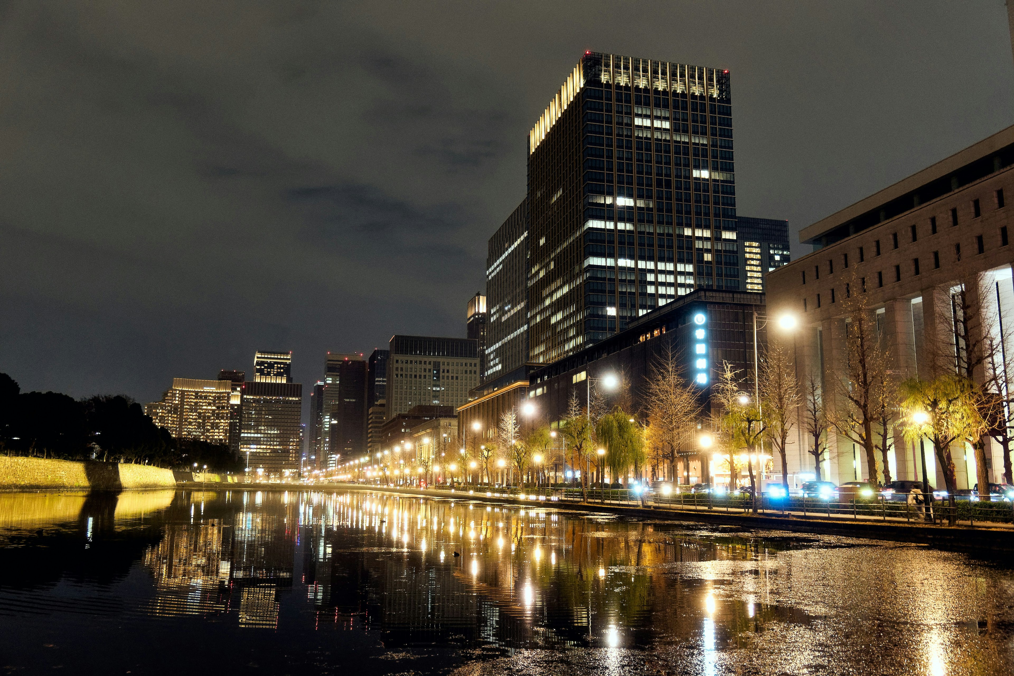 Nighttime cityscape with reflections of buildings and streetlights on the water a calm riverside