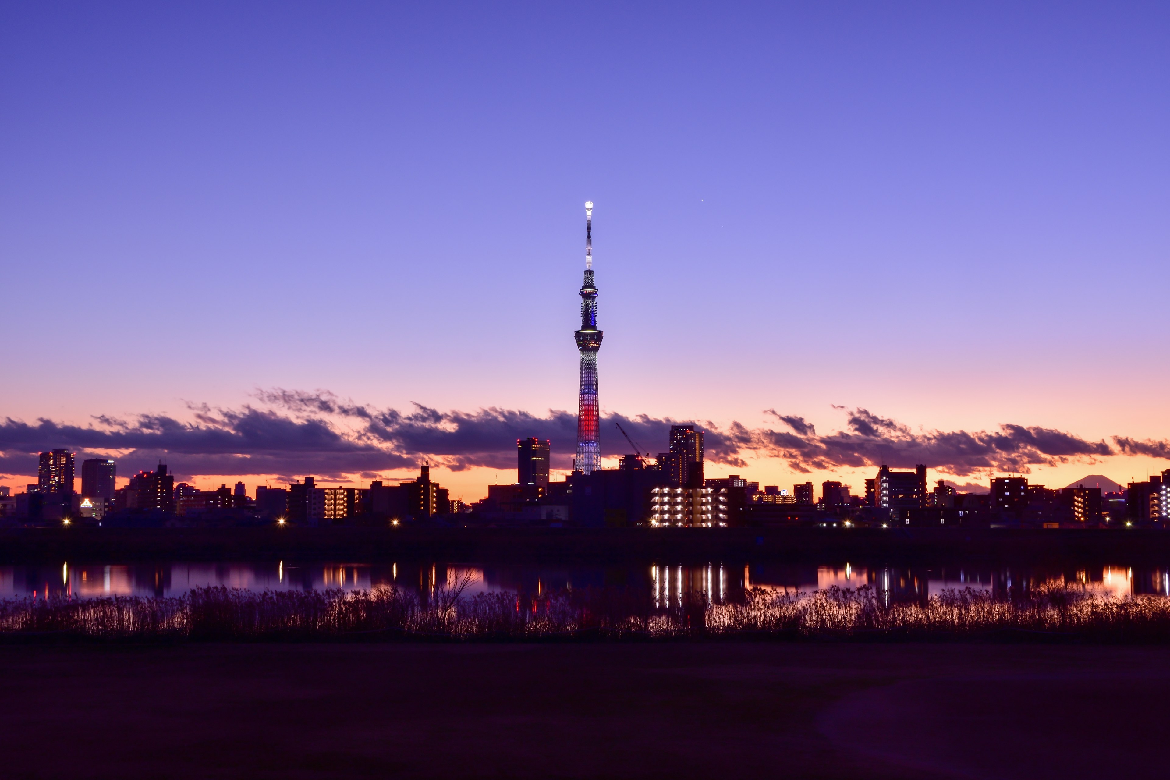 Silhouette del Tokyo Skytree contro un cielo al crepuscolo che si riflette nell'acqua