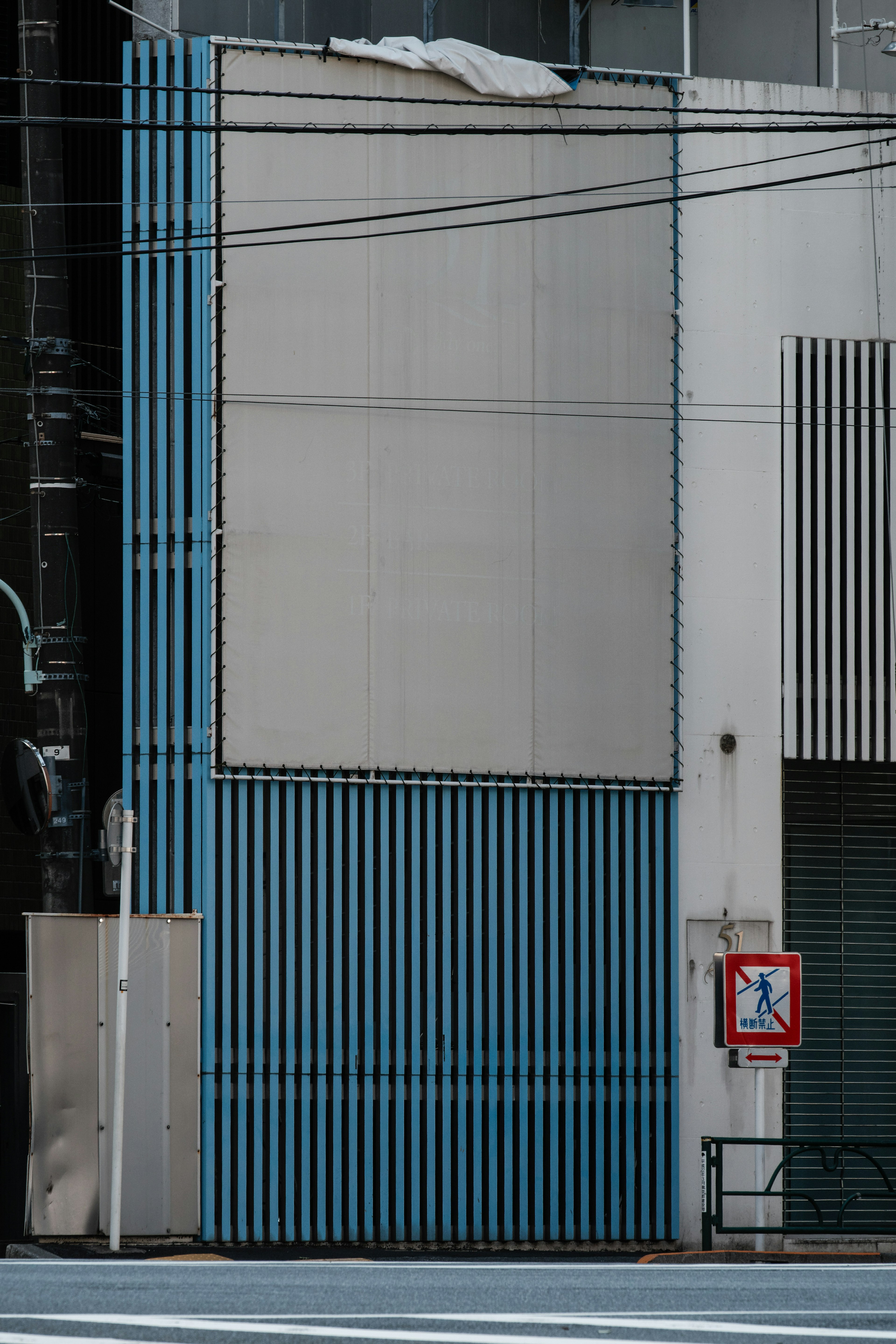 Extérieur d'un bâtiment avec un mur rayé bleu et une section vide