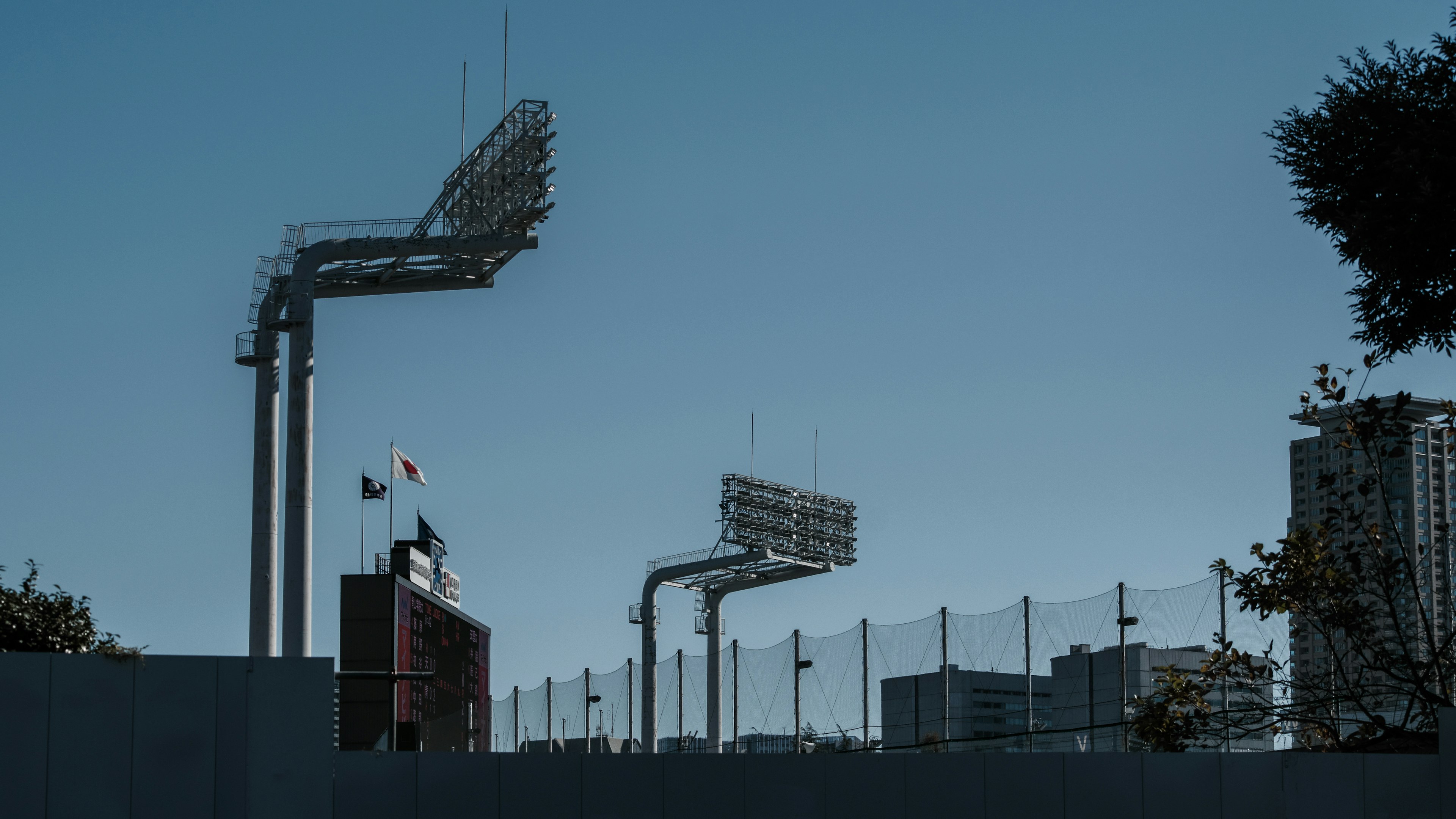 Sports facility lighting towers and advertising billboards under a blue sky