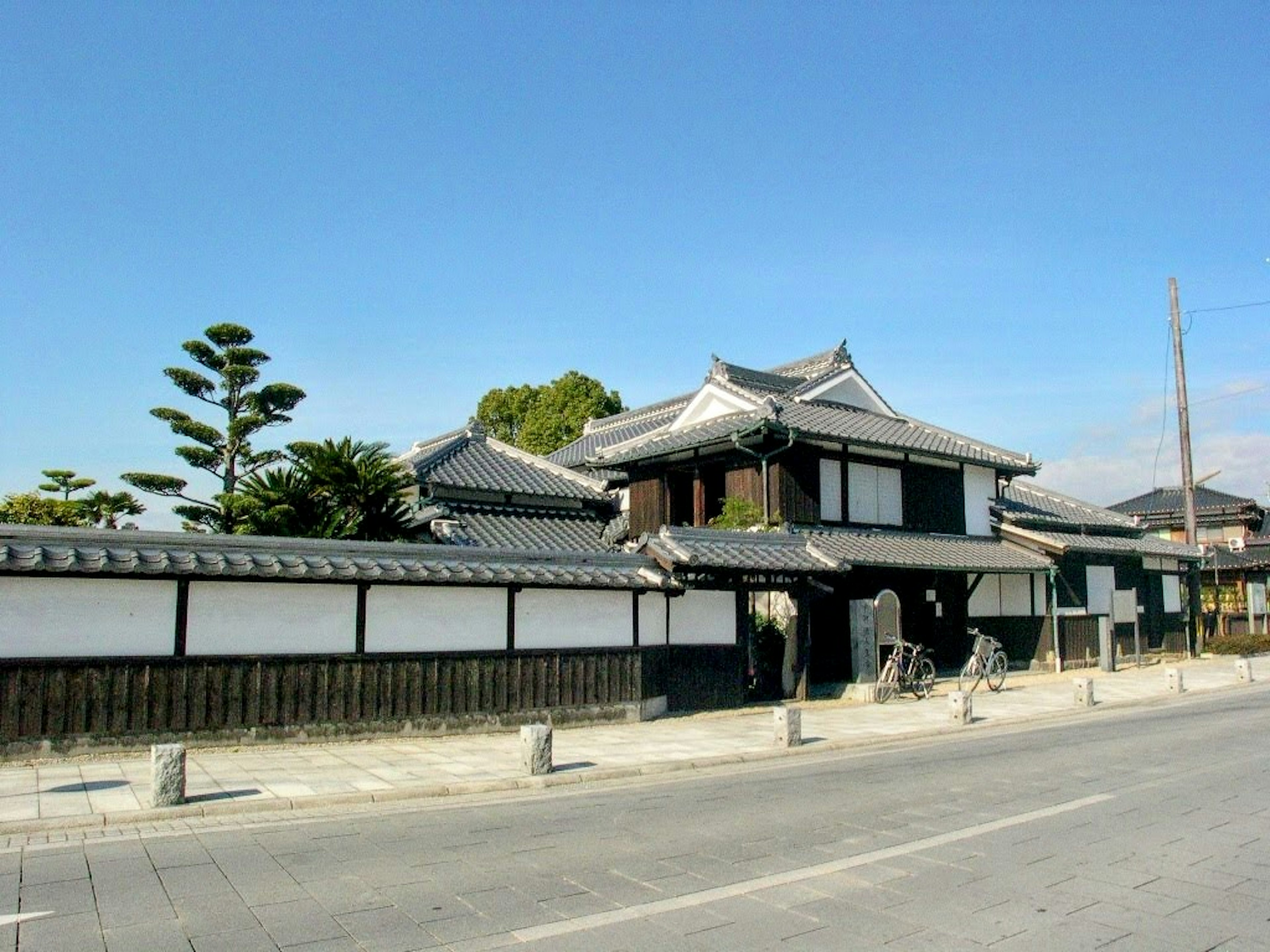 Rumah tradisional Jepang dengan dinding putih dan vegetasi di sekitarnya