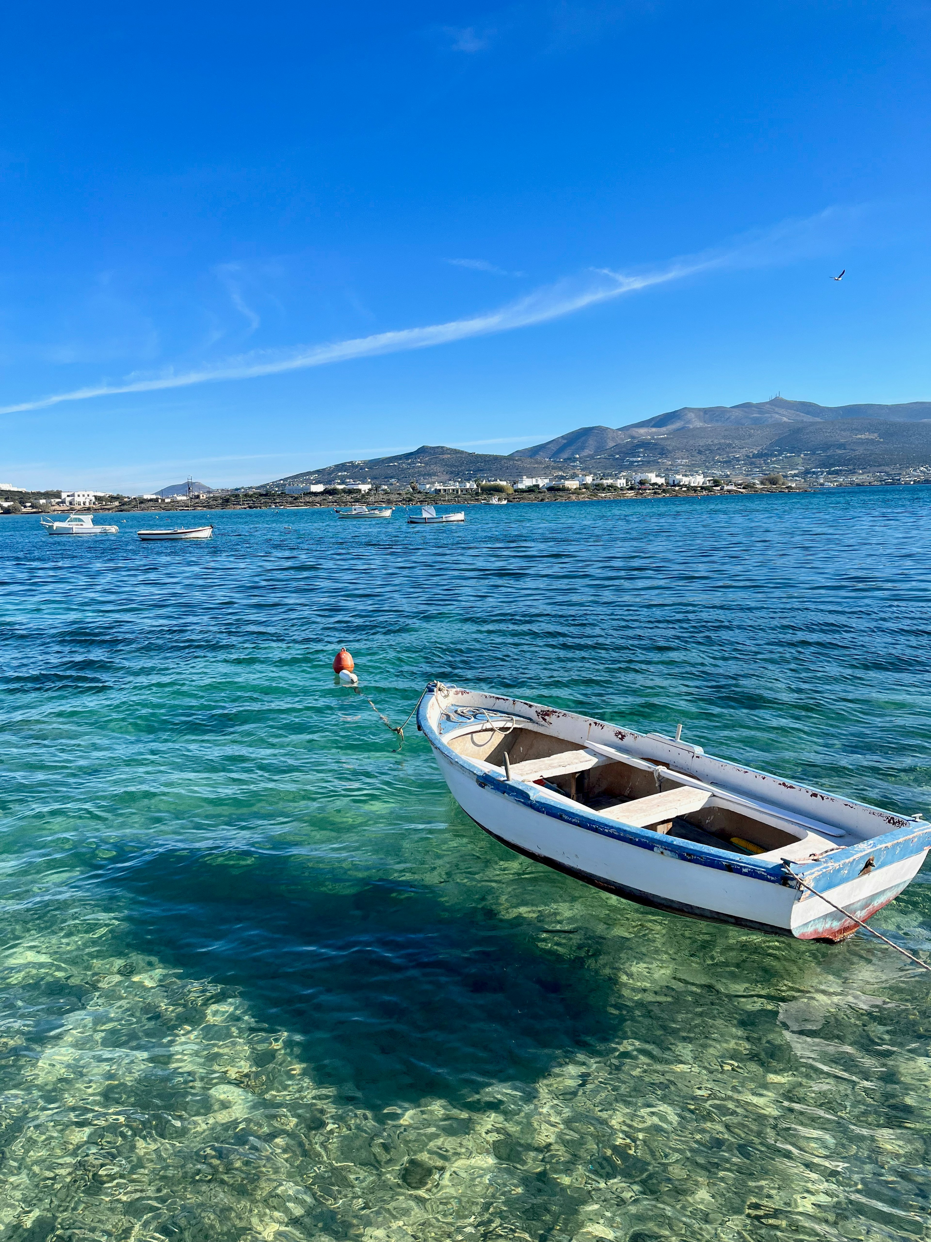 Weißes Boot, das auf blauem Meer mit fernen Bergen schwimmt