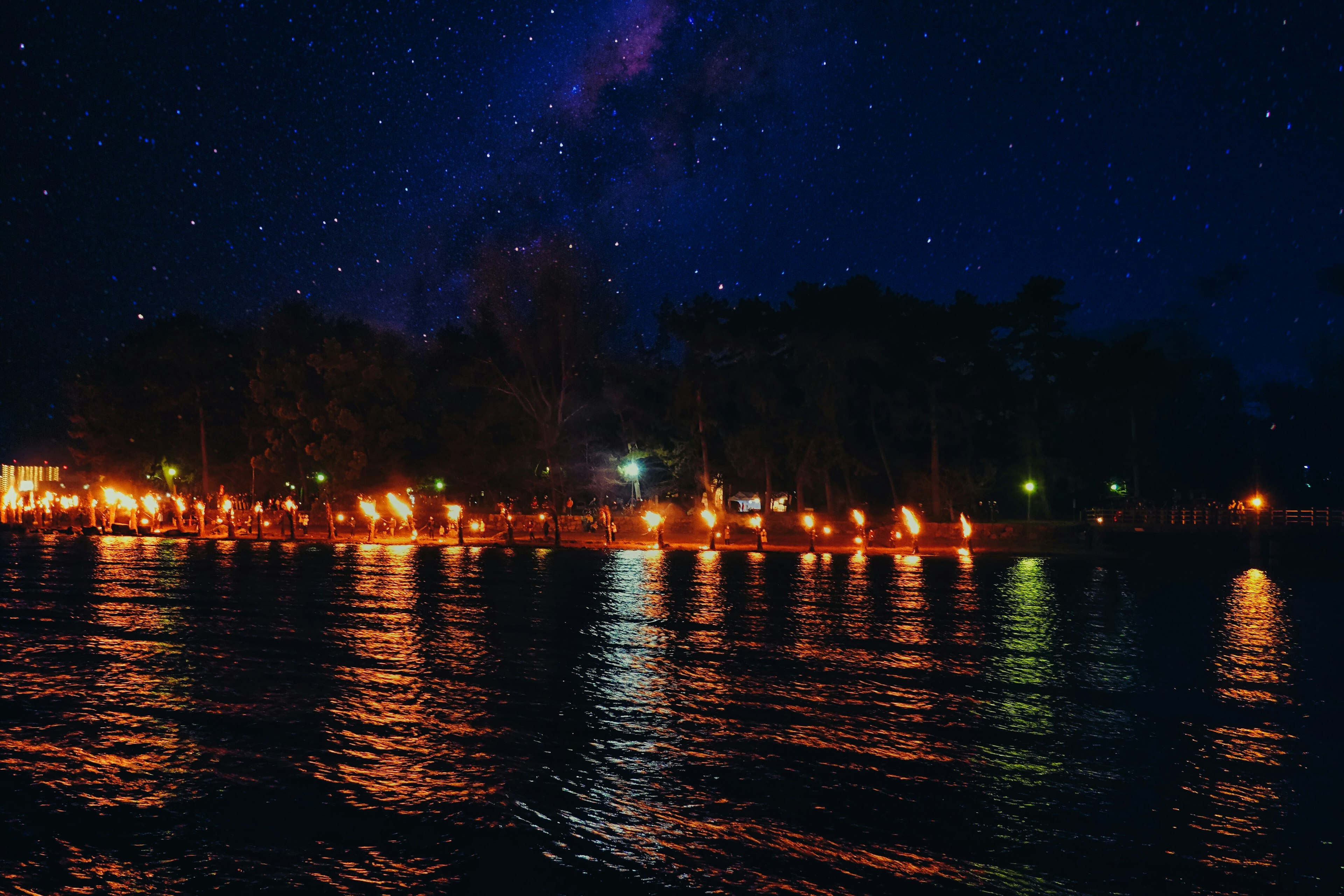 Una scena notturna serena con stelle che brillano nel cielo e luci che si riflettono sul lago