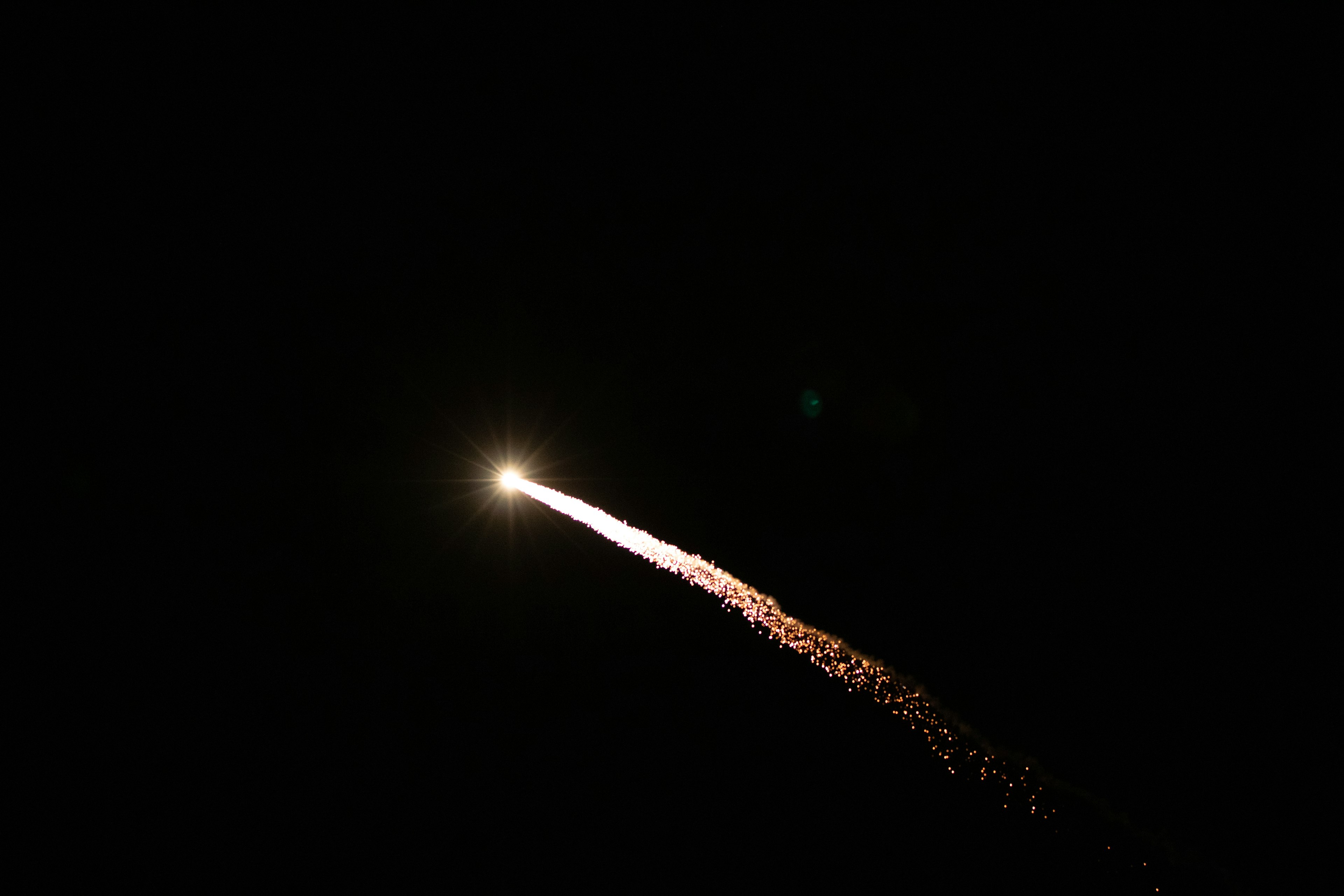 Rocket launching into the night sky with bright light and trailing sparks