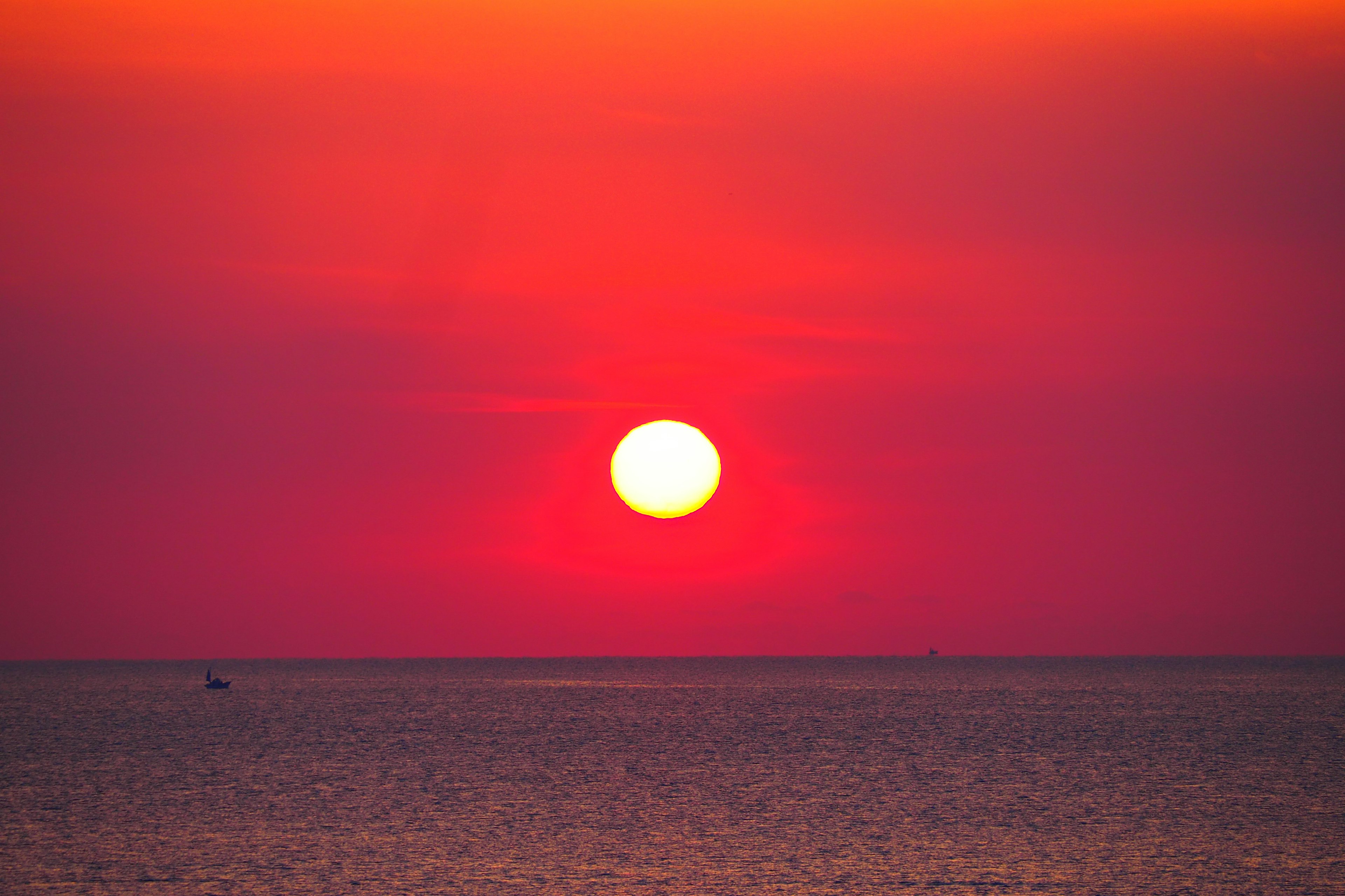 海上美麗的日落，巨大太陽與鮮豔的紅色天空