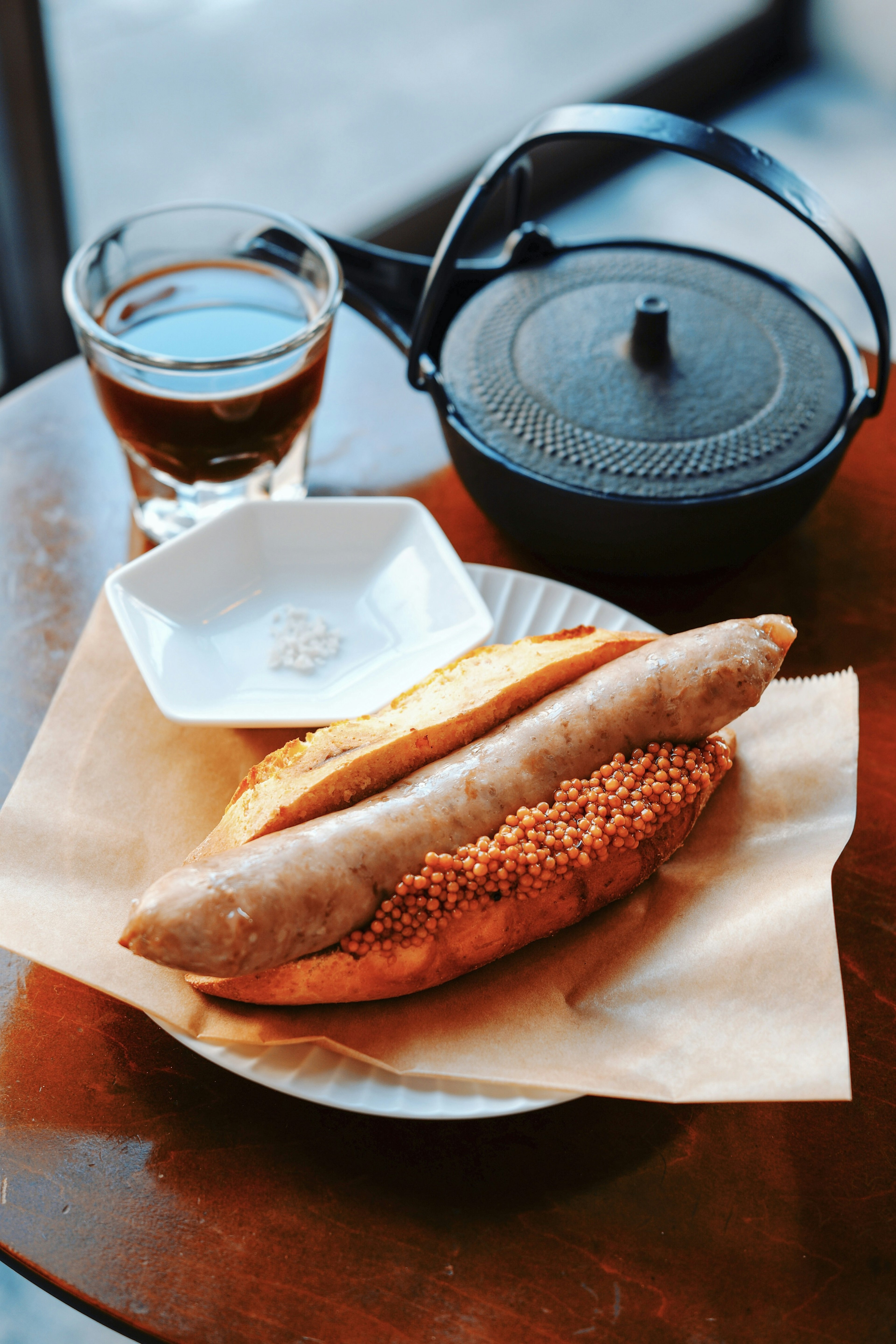 Sausage and bread sandwich on a table with tea