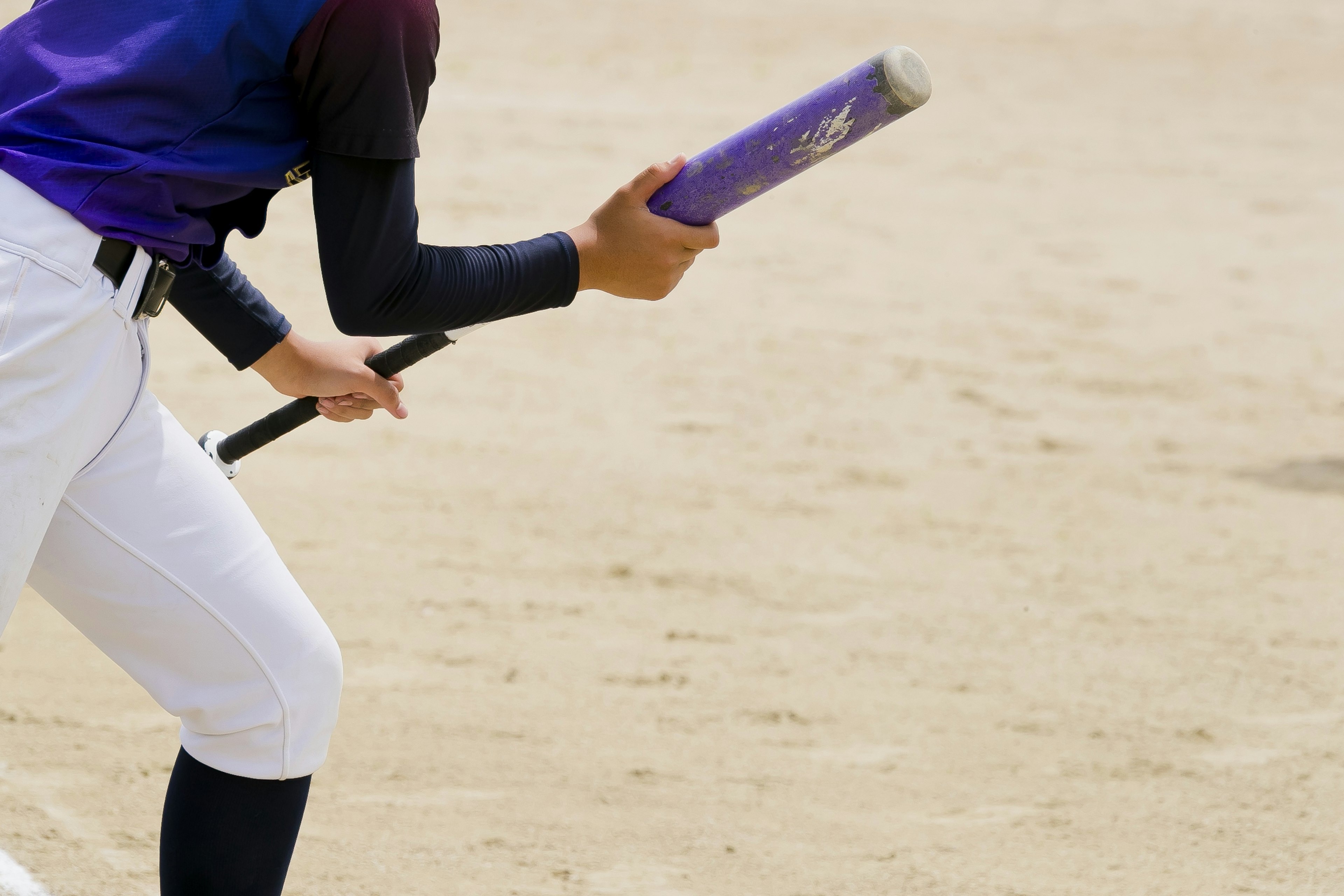 Primo piano di un giocatore di baseball che tiene una mazza viola