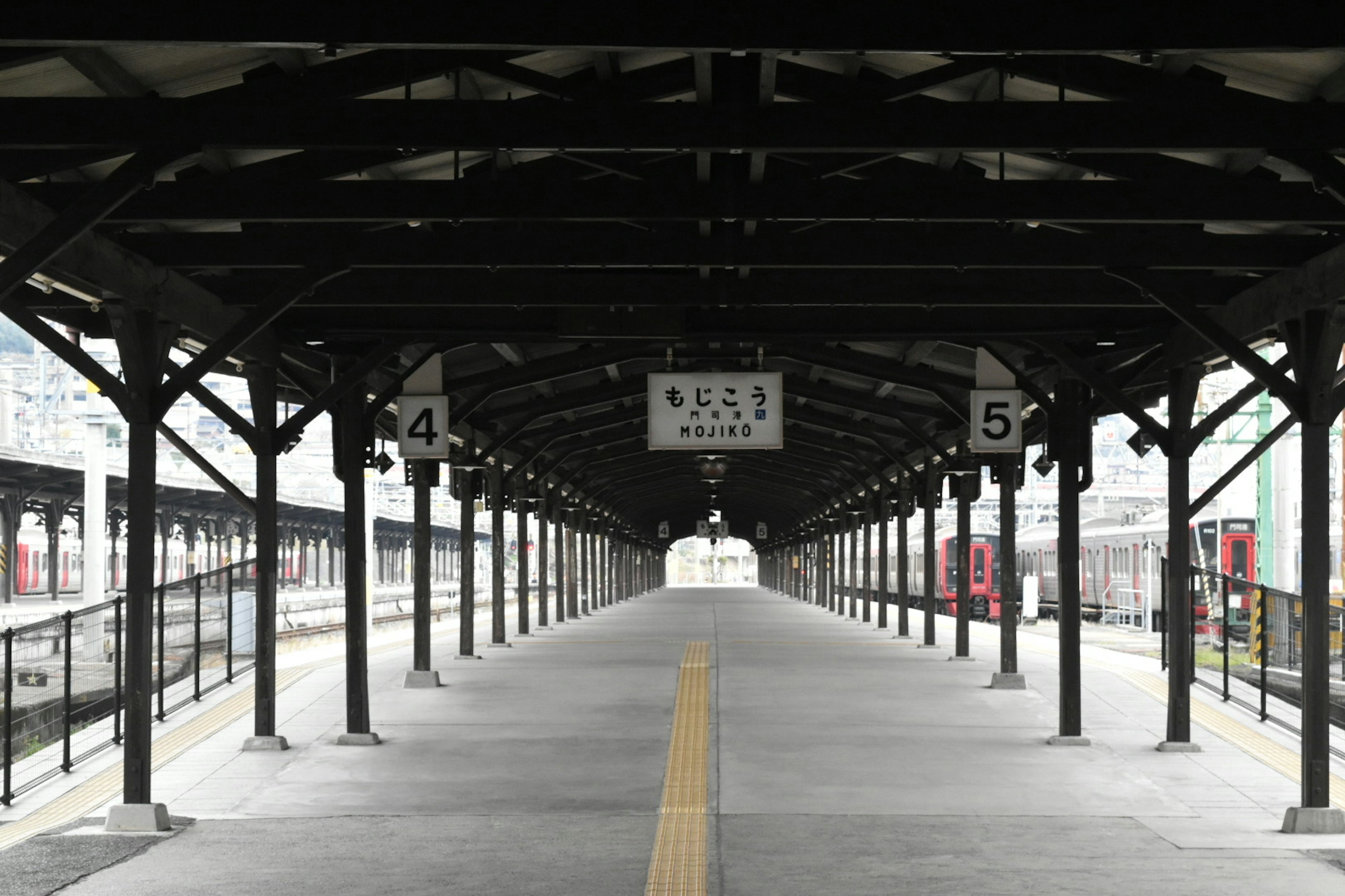 Empty train platform with black wooden roof and overhead lights