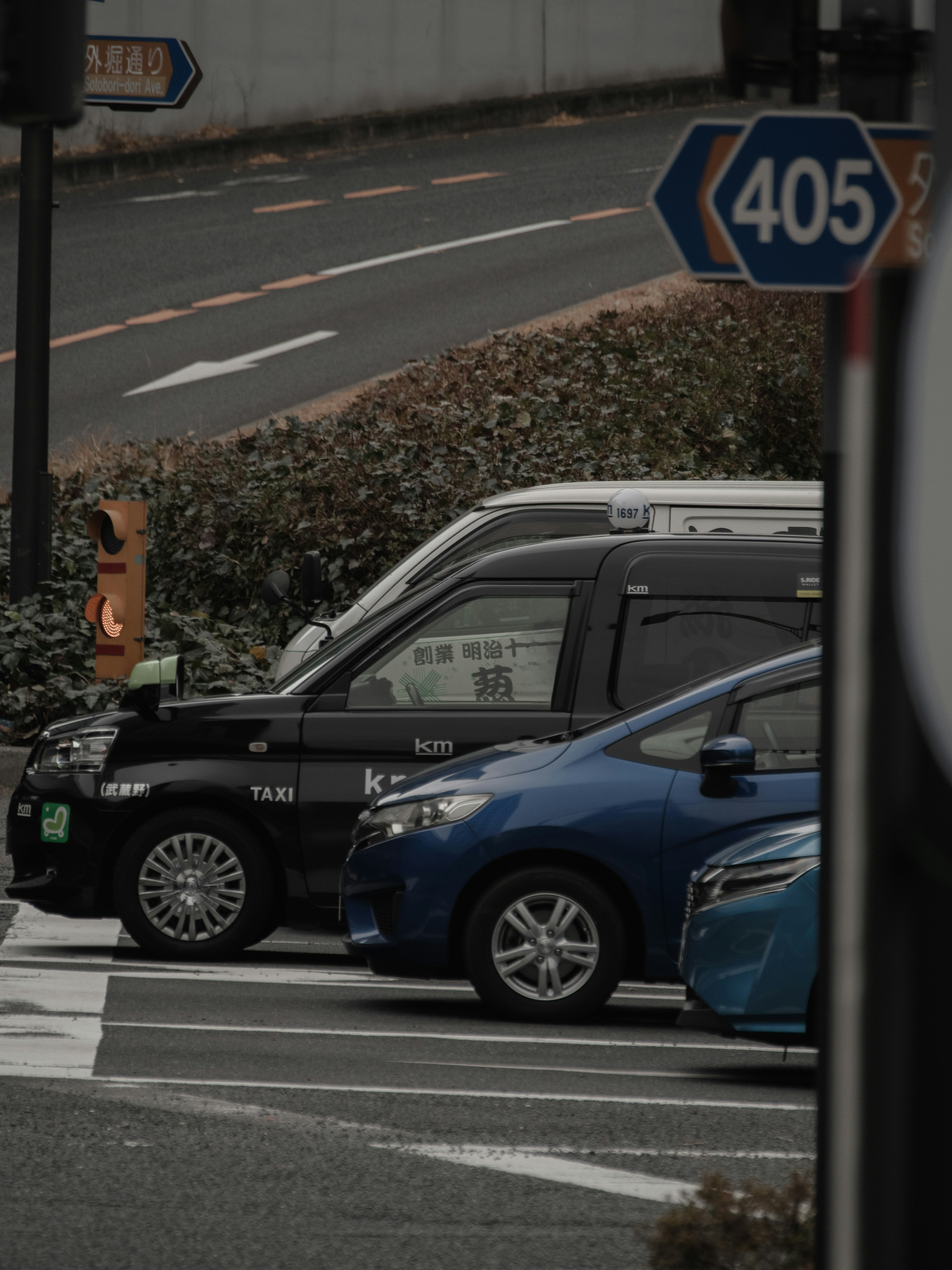 道路に停車した黒いタクシーと青い車が並ぶ風景