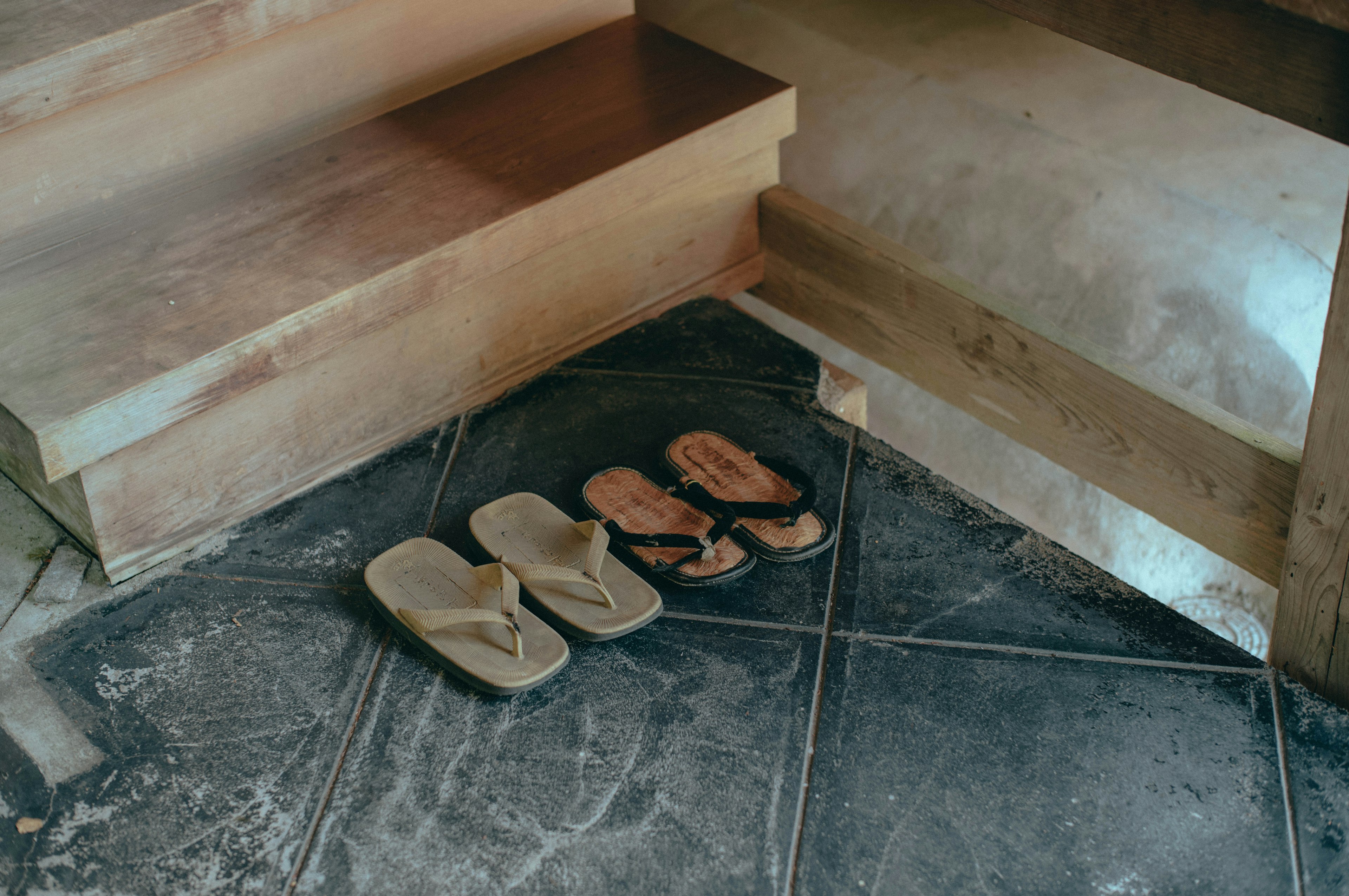 Group of sandals and shoes placed near wooden stairs