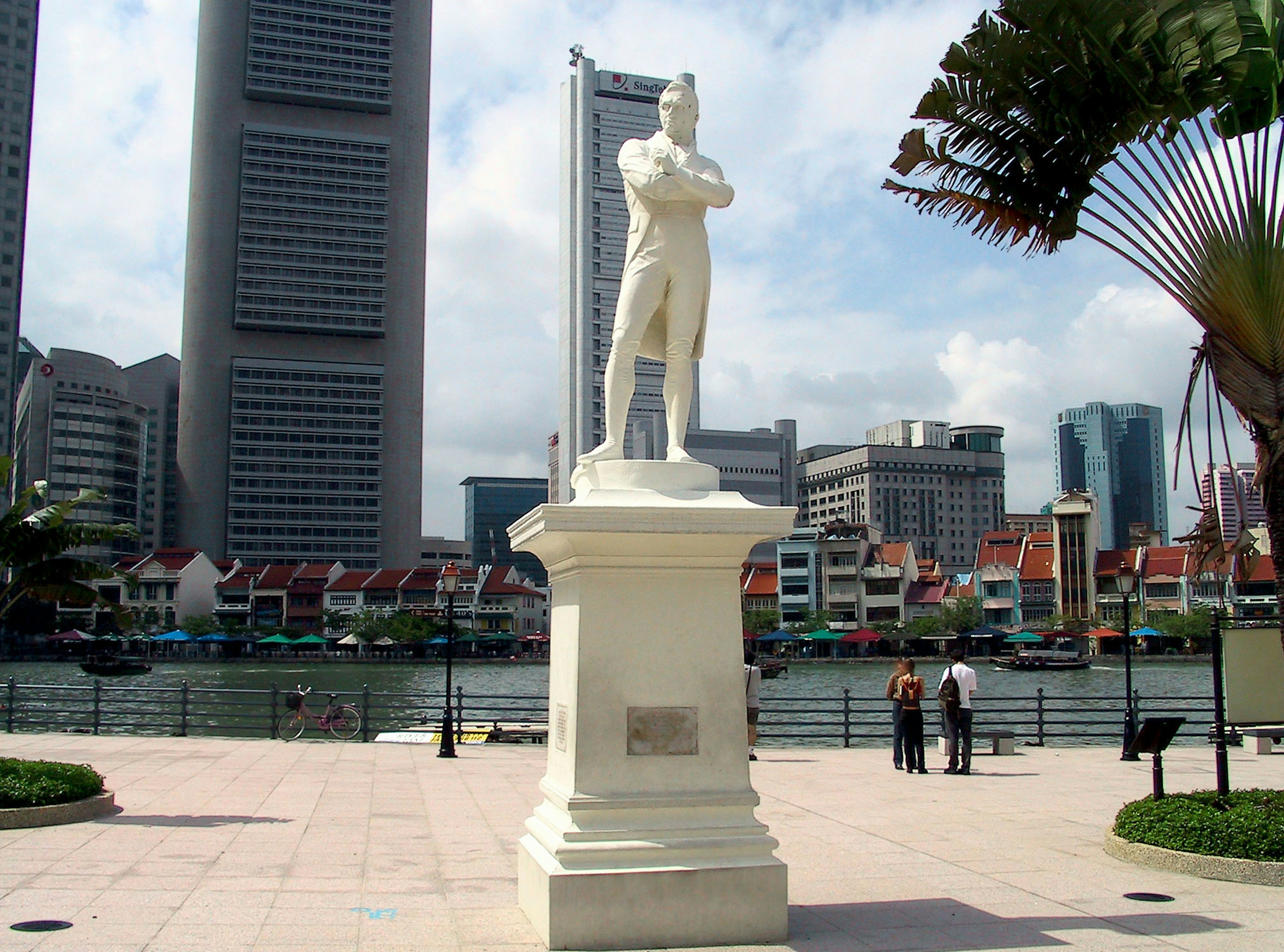 Statua bianca che si erge lungo il fiume a Singapore con grattacieli sullo sfondo