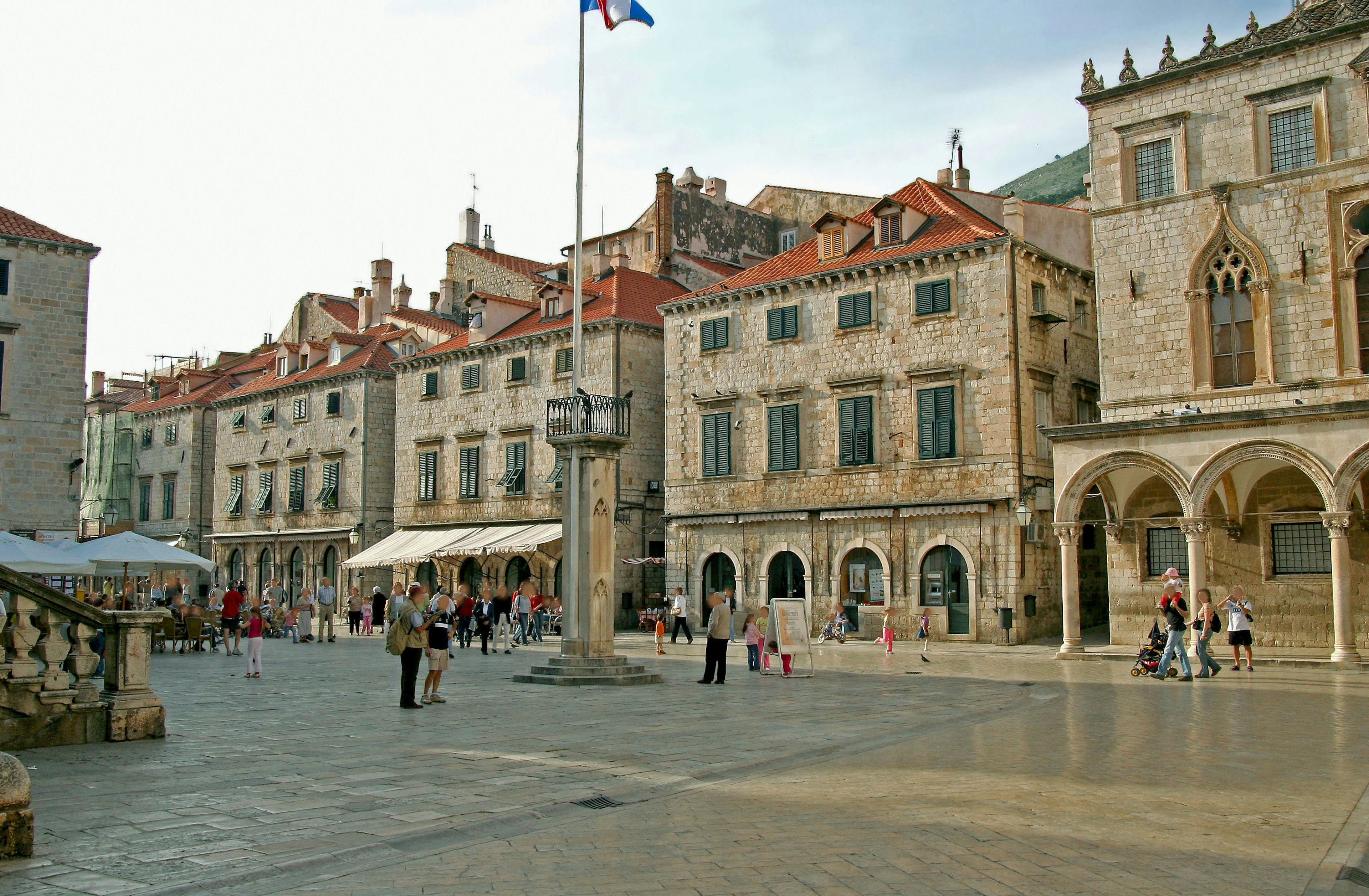 Blick auf einen Platz in der Altstadt von Dubrovnik mit historischen Steingebäuden und roten Dächern