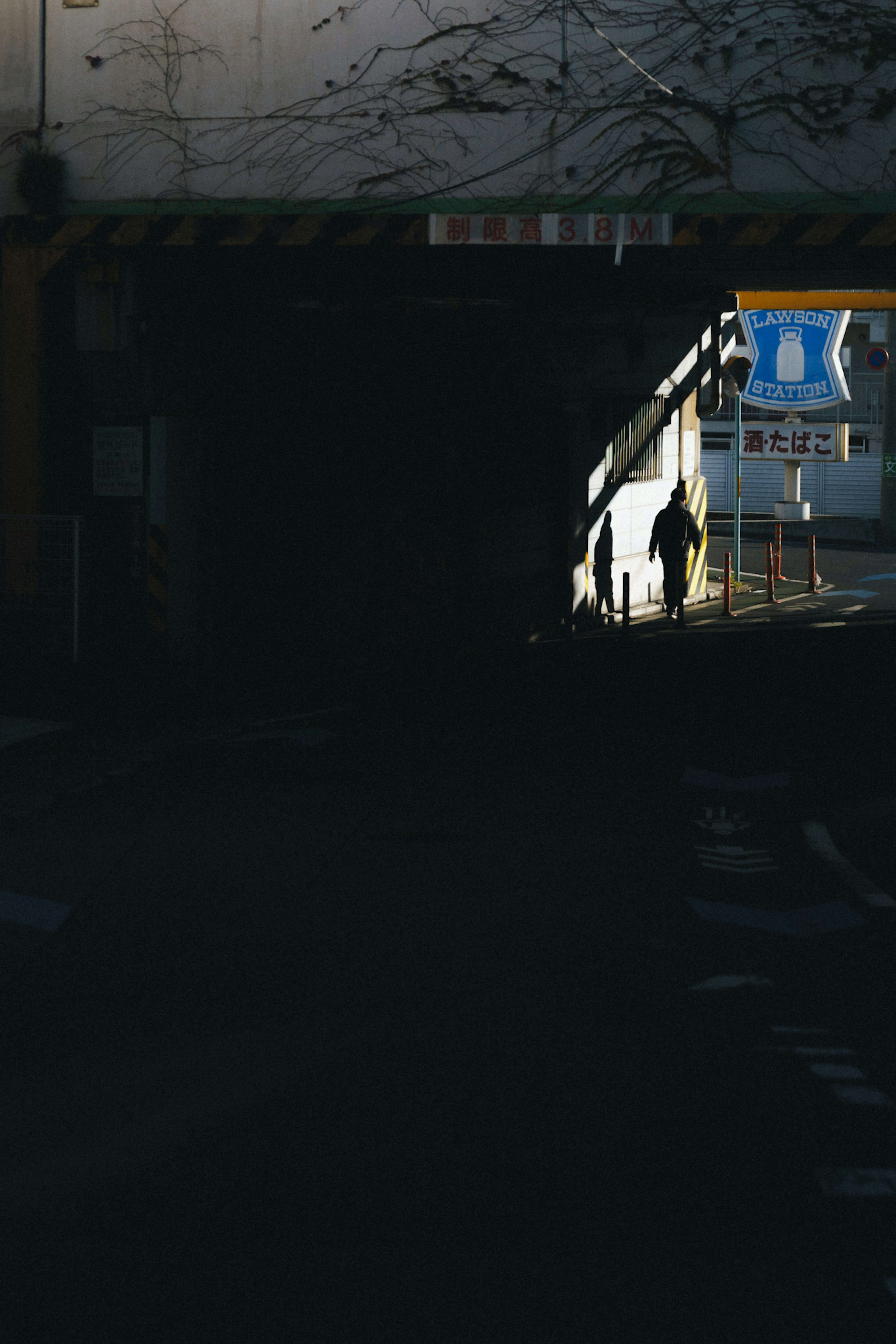 Schatten einer Person, die am Ausgang eines dunklen Tunnels mit einem blauen Schild steht