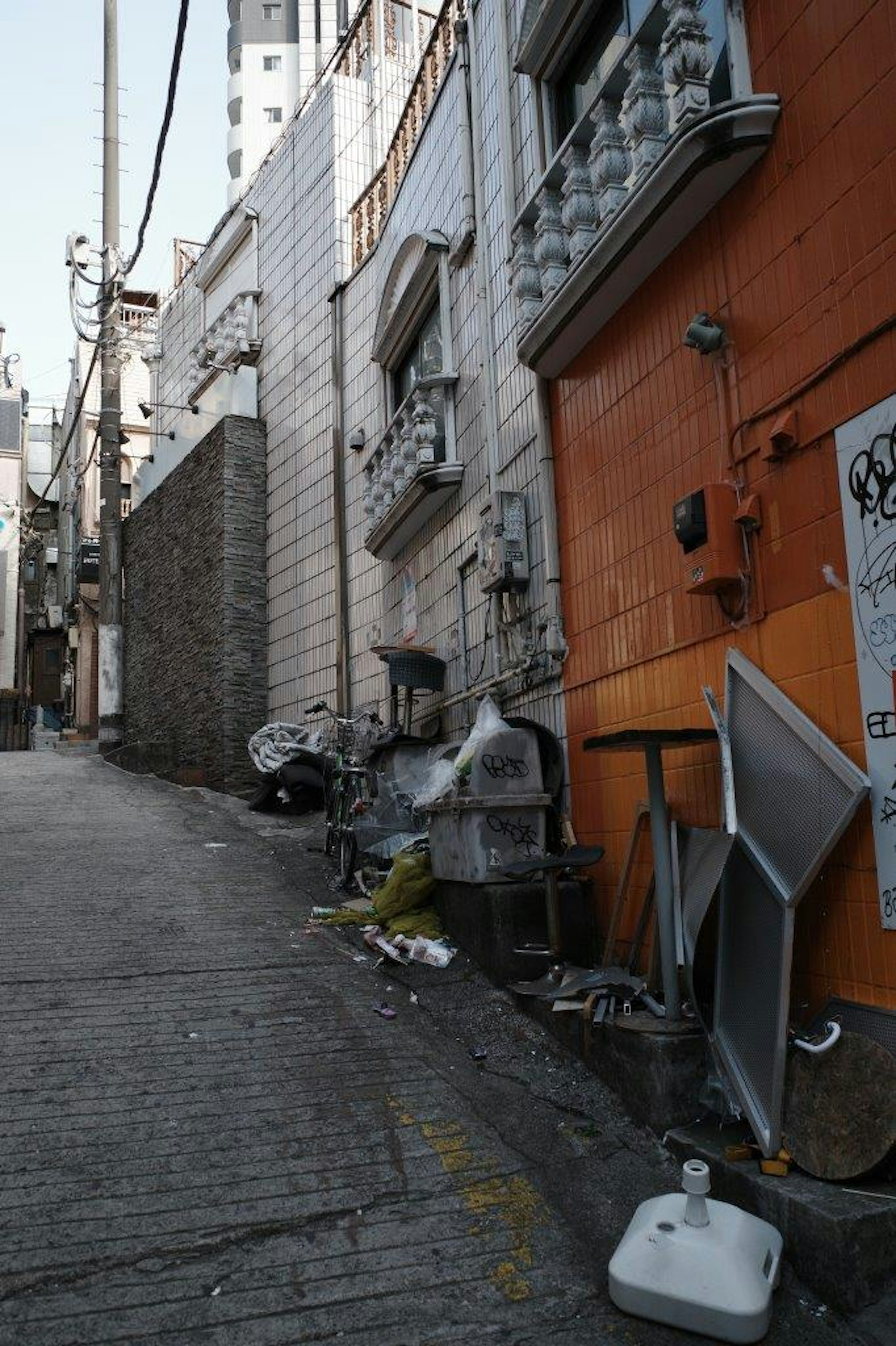 A narrow alleyway filled with trash and discarded items