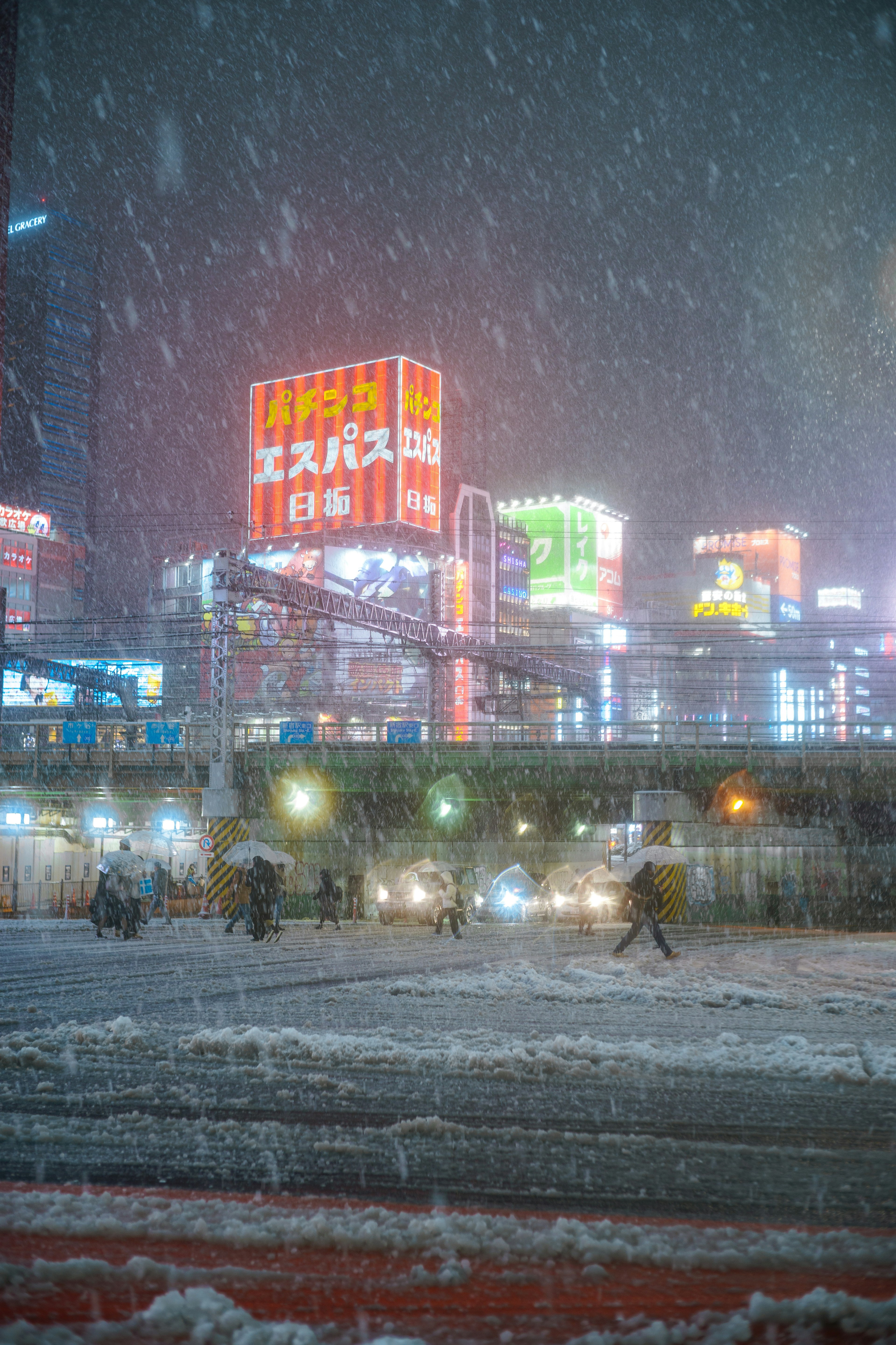 雪の中の都市風景に明るいネオン看板と人々が歩いている