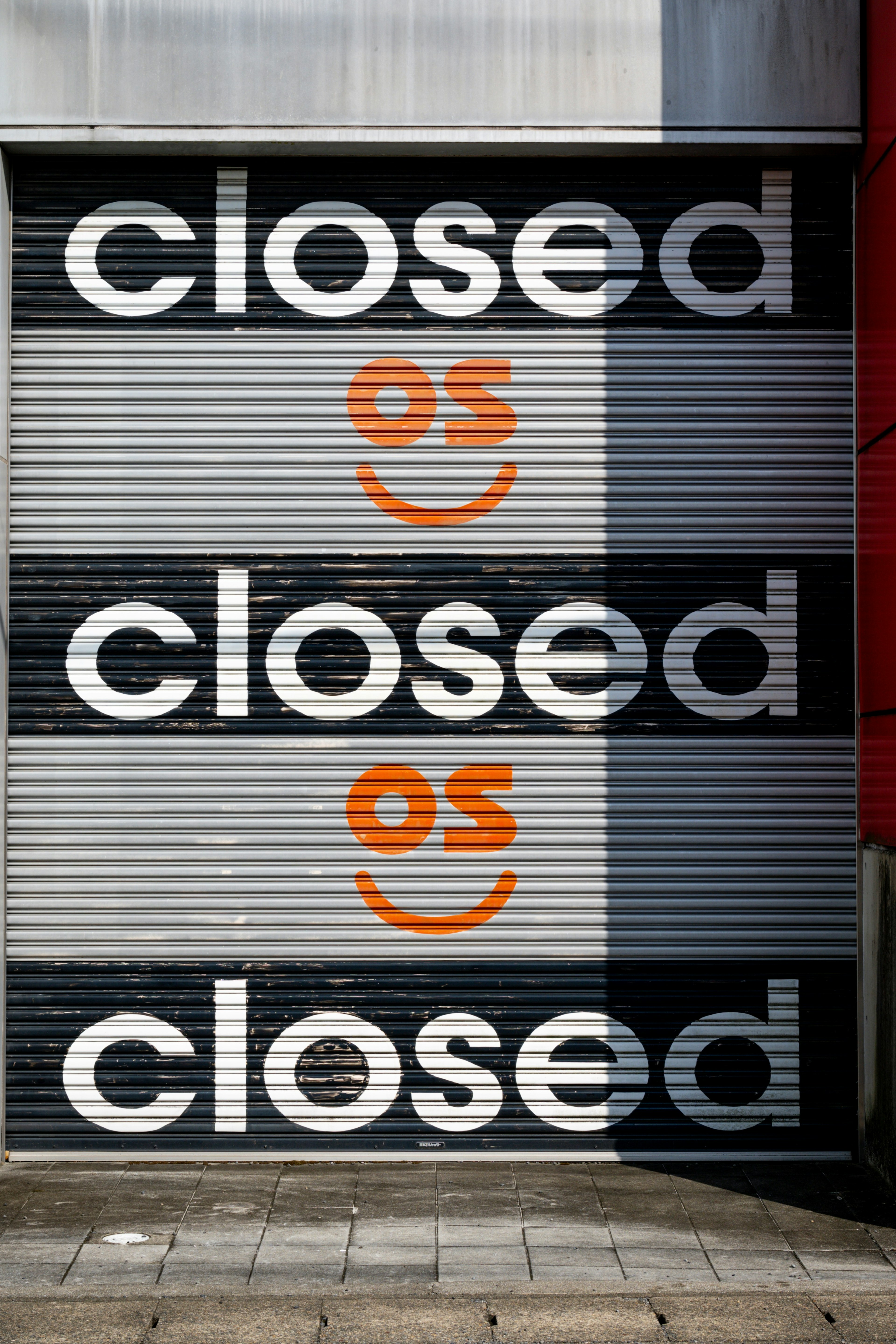 Closed shop shutter featuring large text and a smiley face in orange