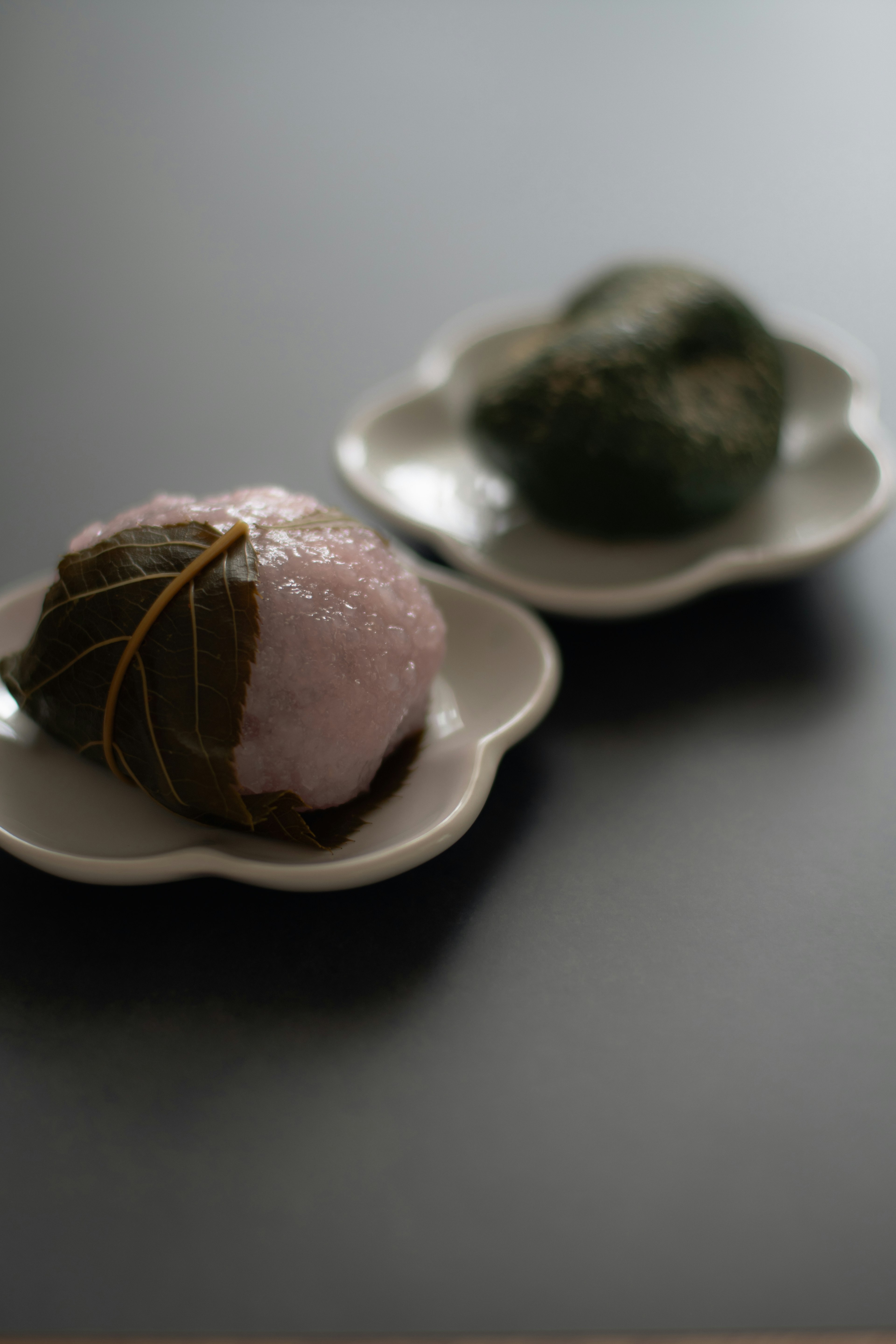 Two traditional Japanese sweets in pink and green on decorative plates