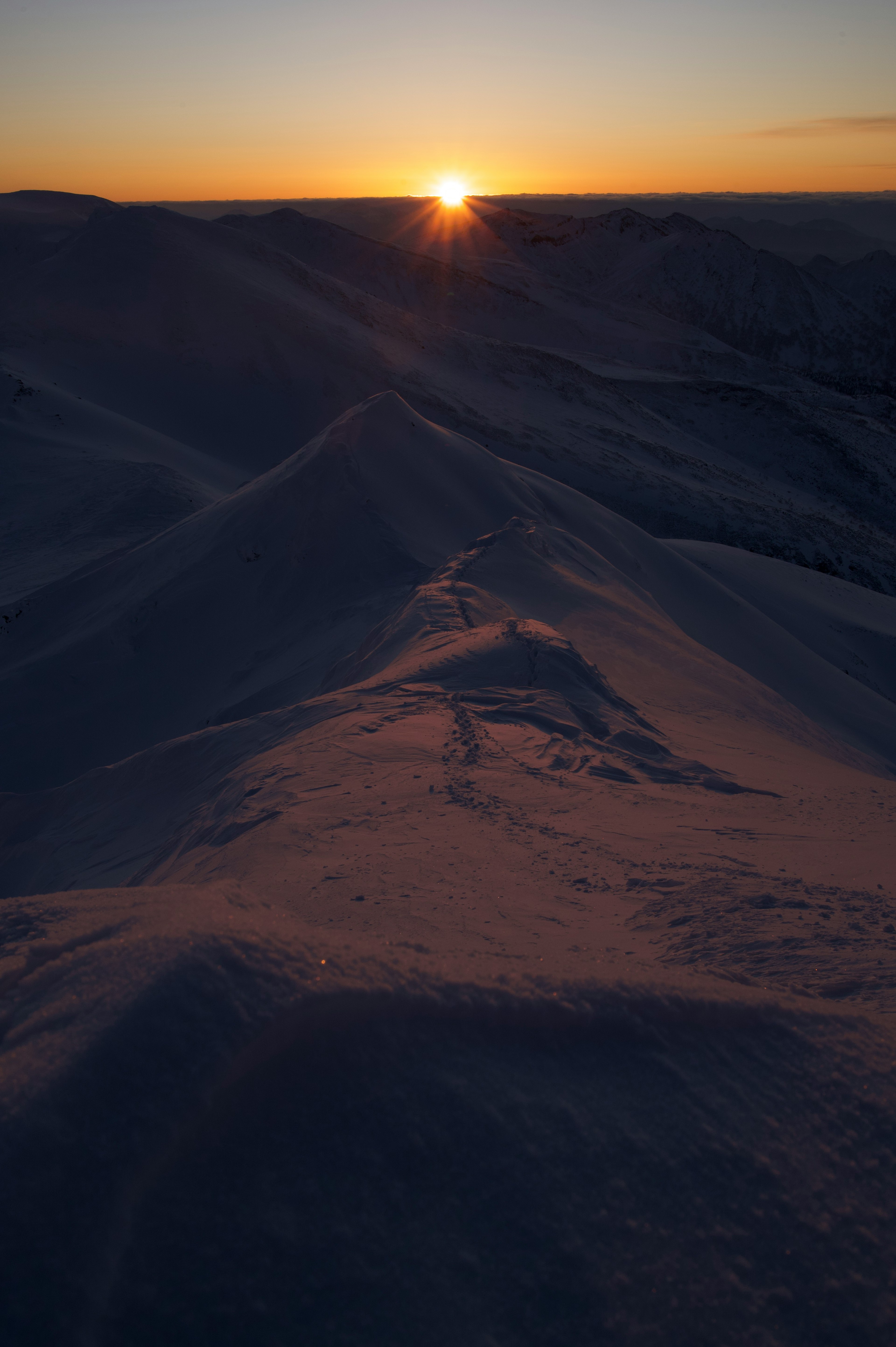 Sunset over snow-covered hills with shadows