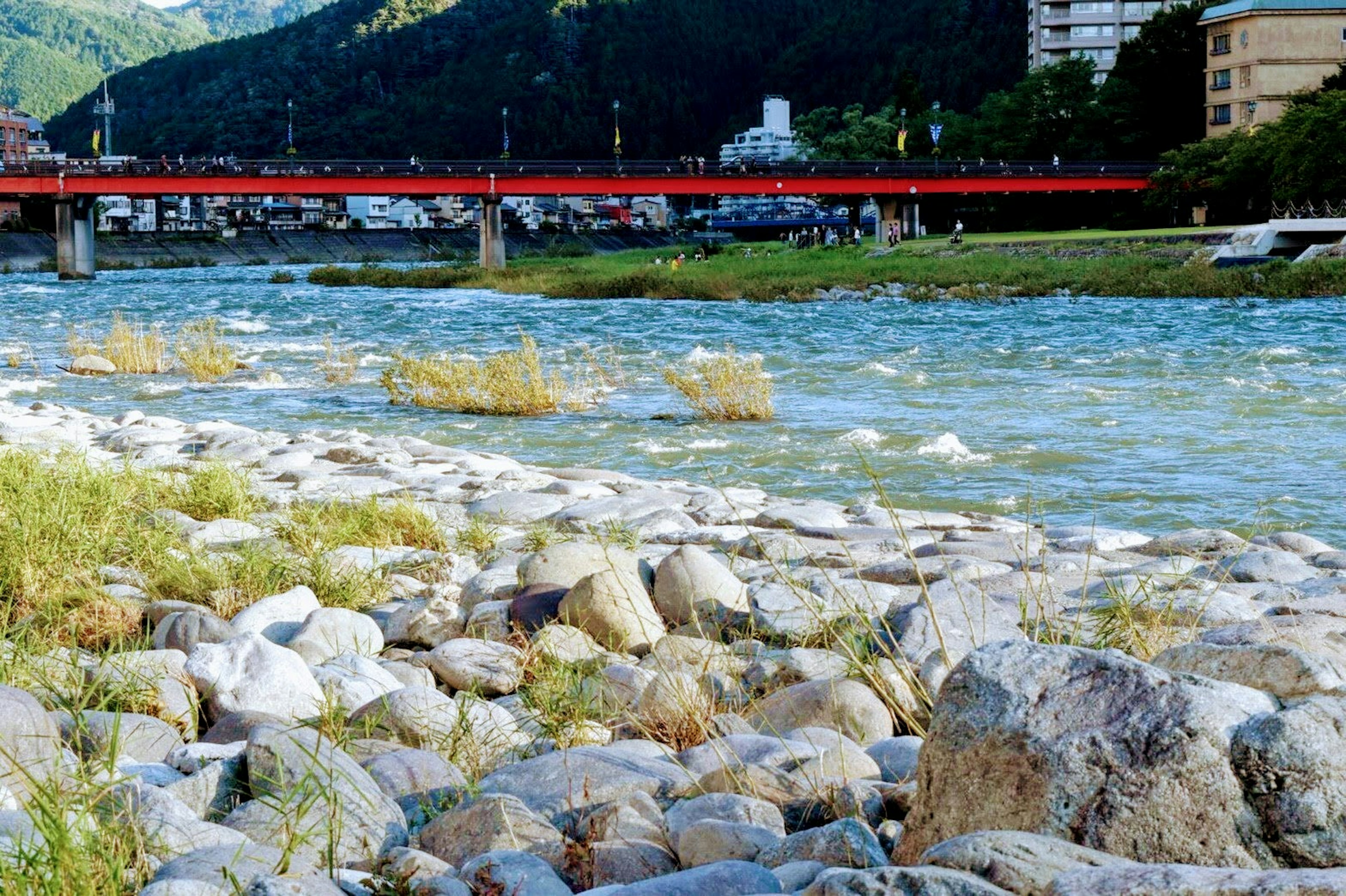 Vue panoramique d'un pont rouge sur une rivière avec des pierres