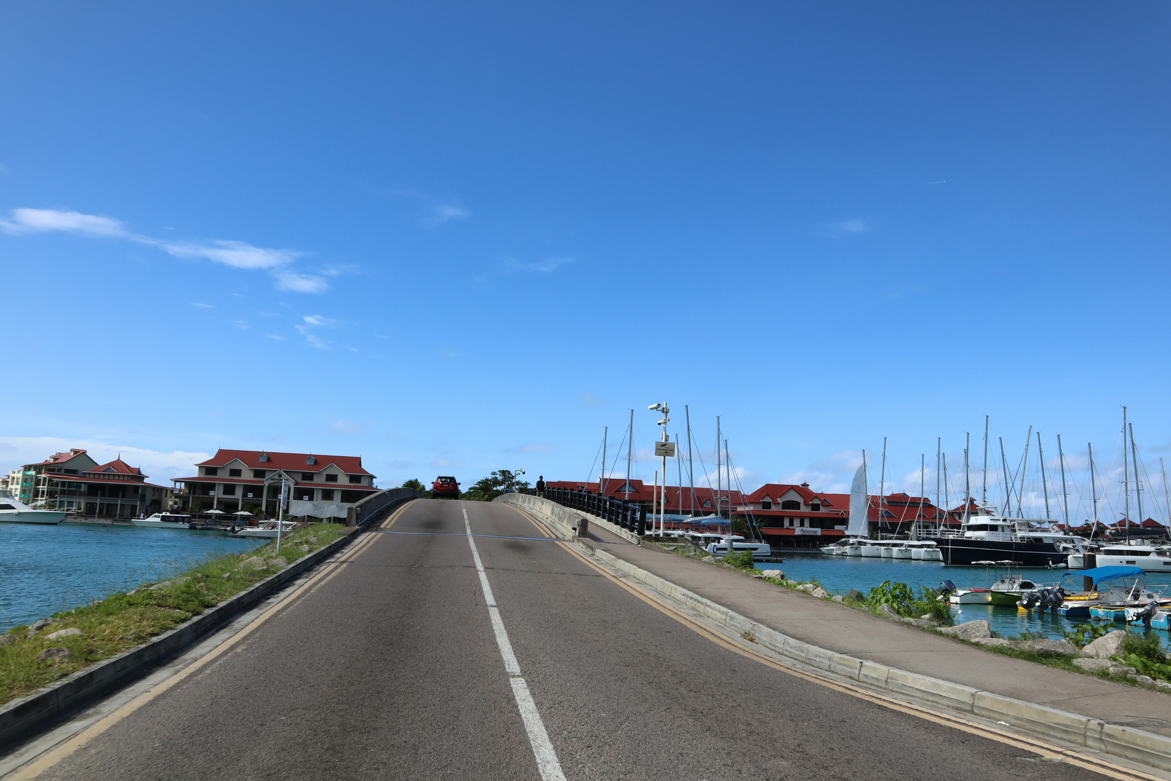 A scenic view of a bridge with yachts docked on one side and blue skies