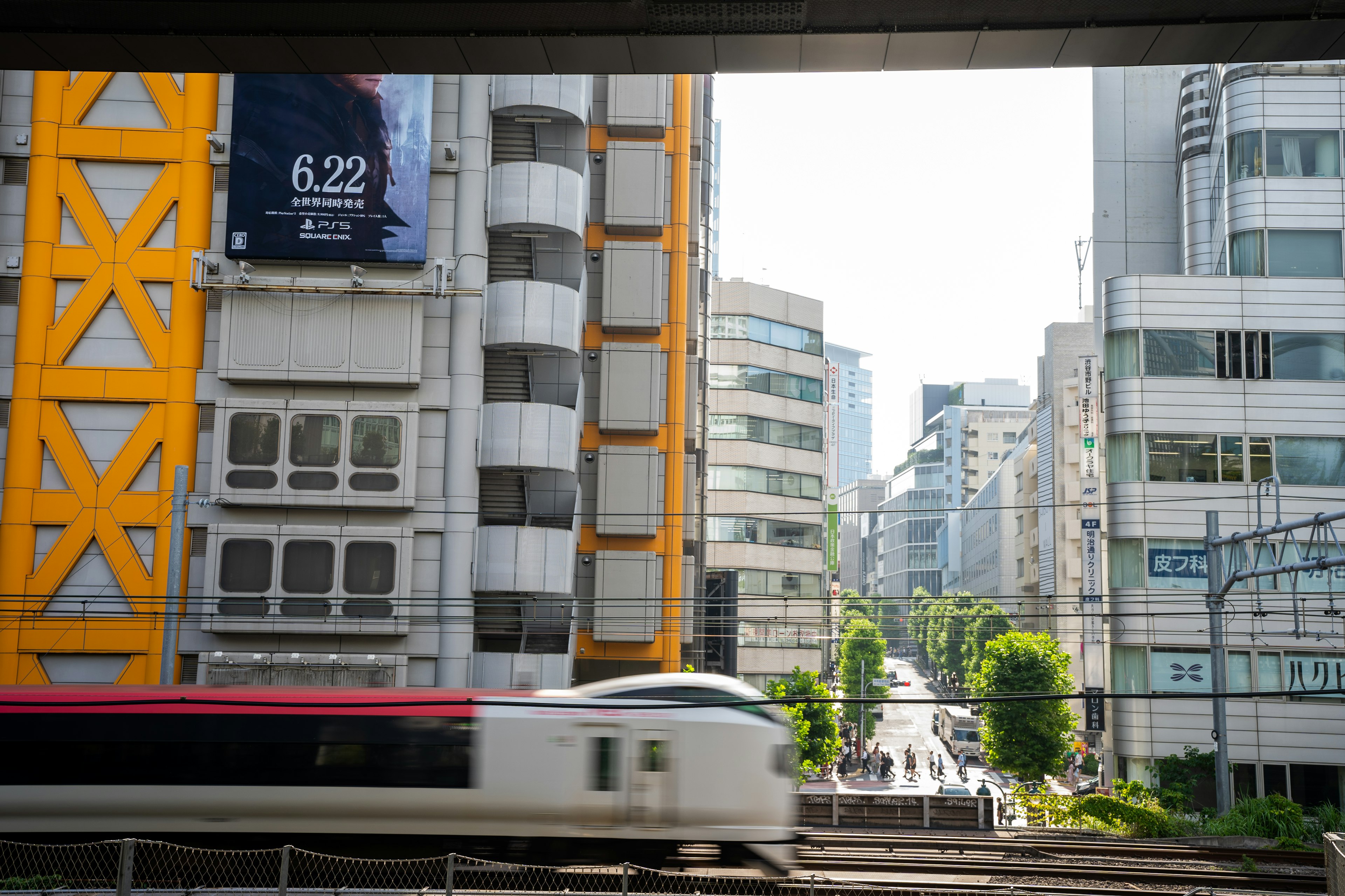 黄色い建物と近代的な高層ビルが並ぶ都市の風景に電車が通過する