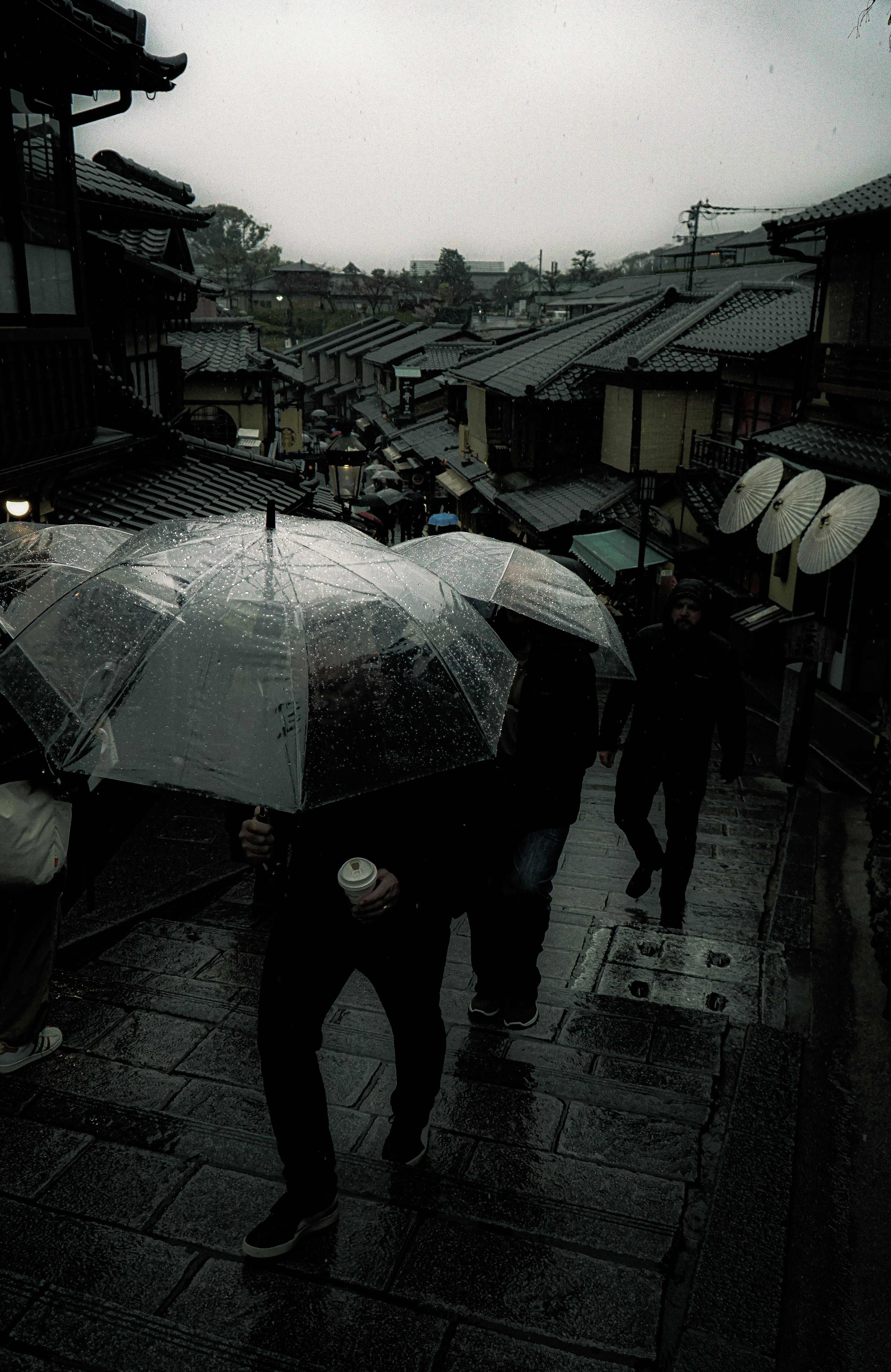 People walking in the rain with umbrellas in a traditional Japanese street