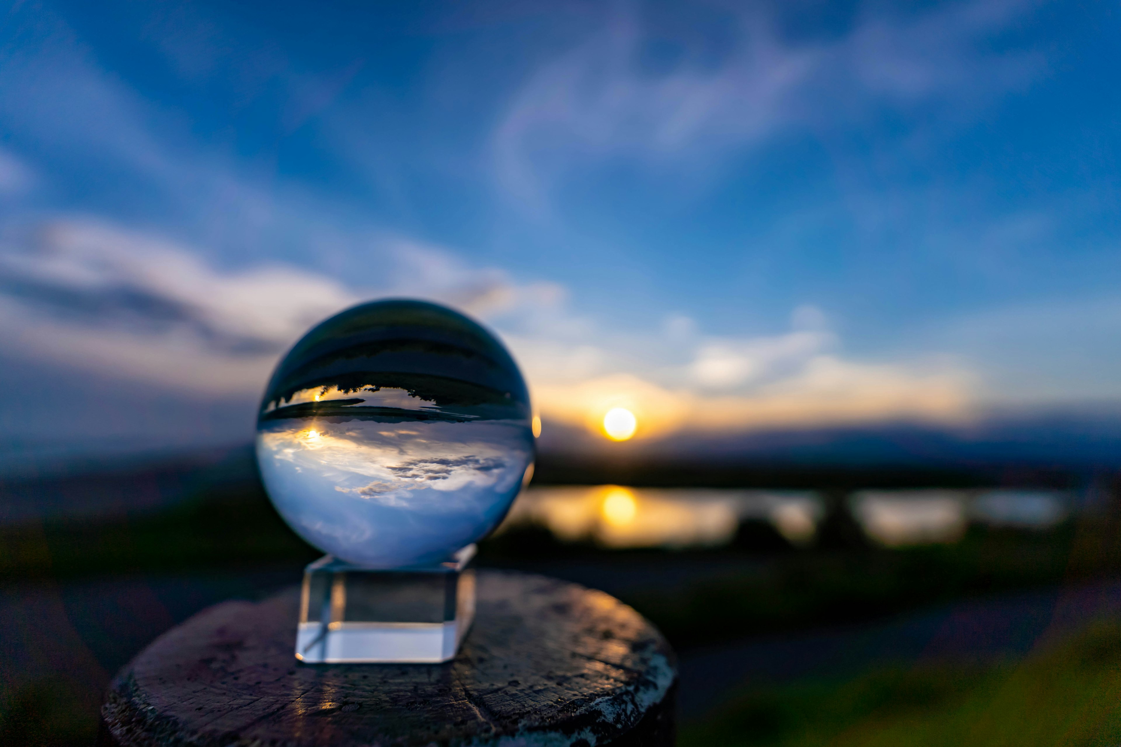 Bola di cristallo che riflette il cielo al tramonto e la superficie dell'acqua