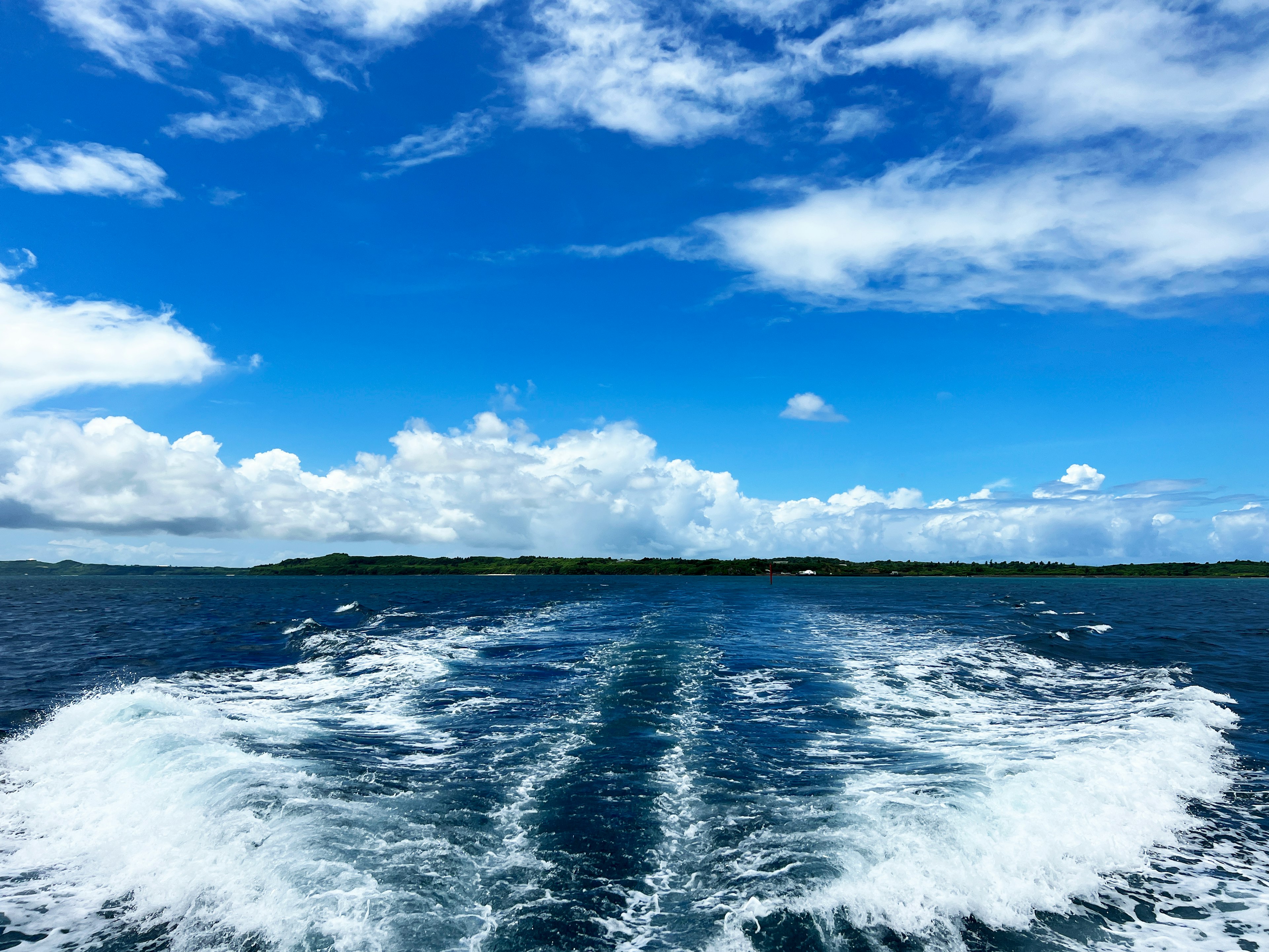 Blick auf das Meer unter einem blauen Himmel mit weißen Wolken Bootswelle sichtbar