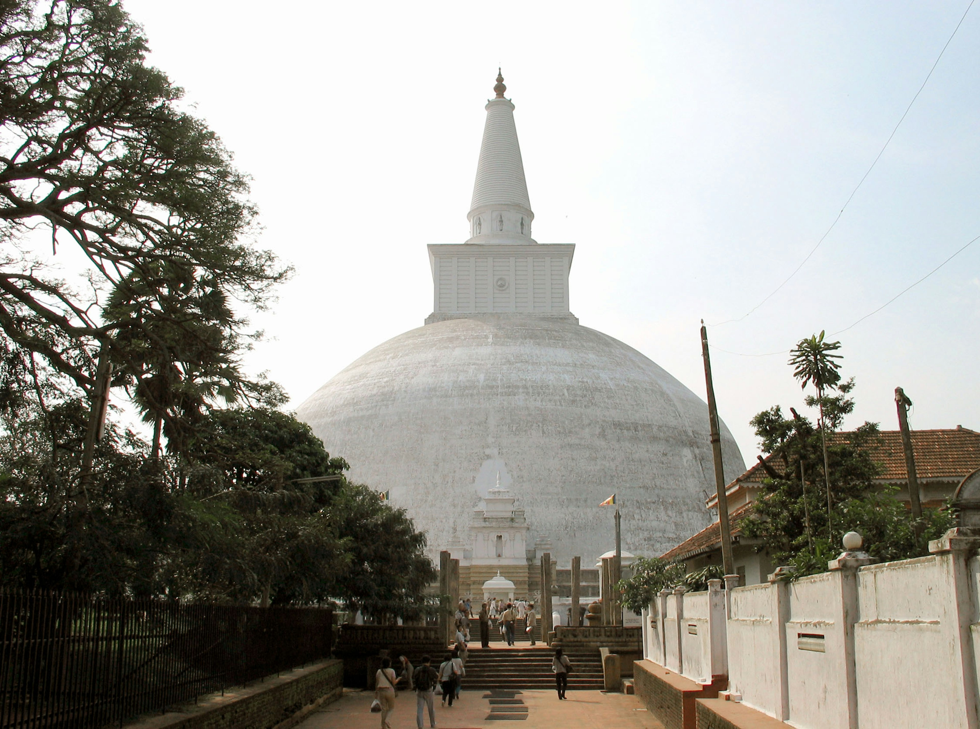 Un grand stupa avec des arbres environnants et des visiteurs