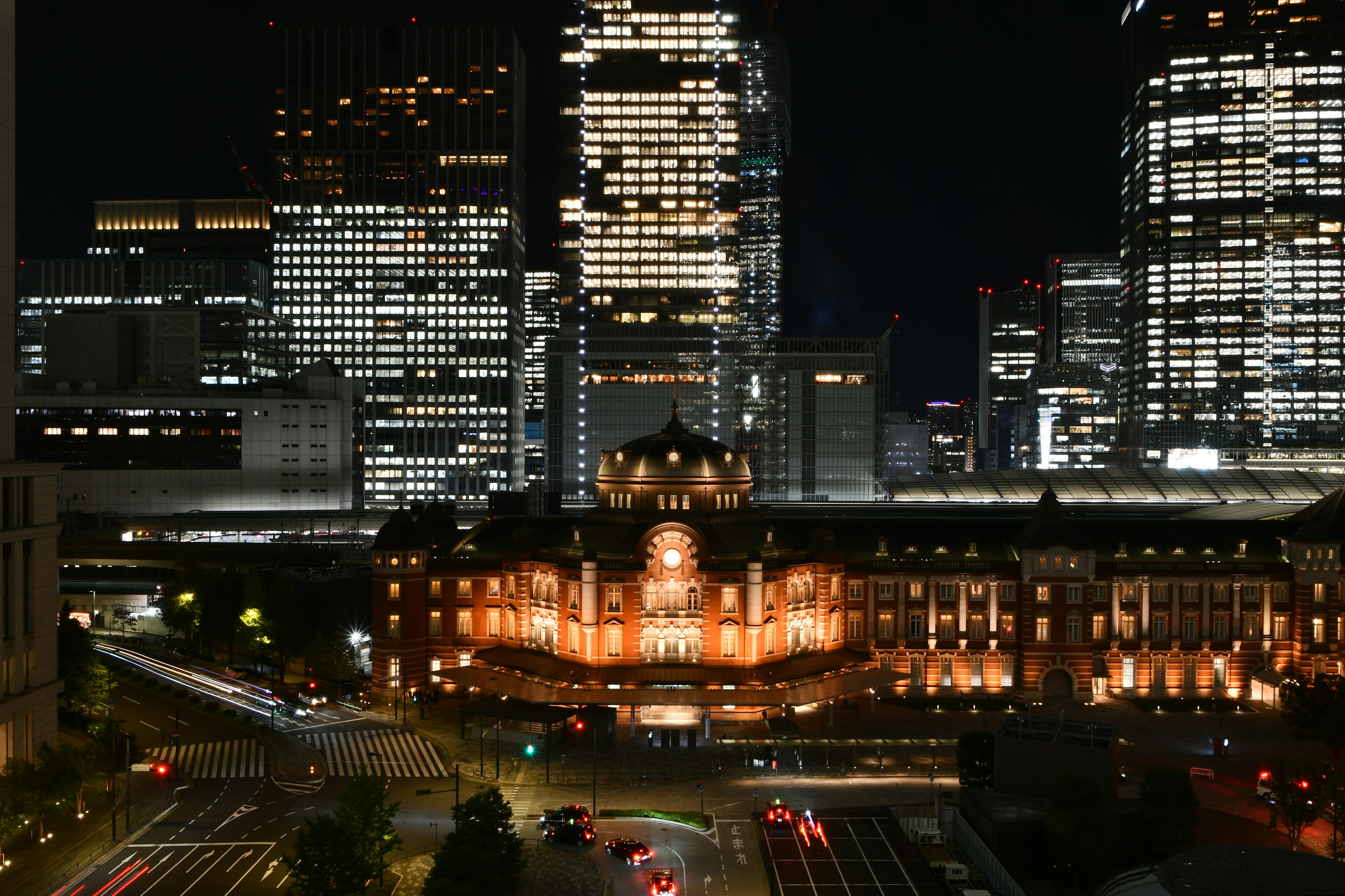 Vista notturna della stazione di Tokyo con grattacieli illuminati sullo sfondo